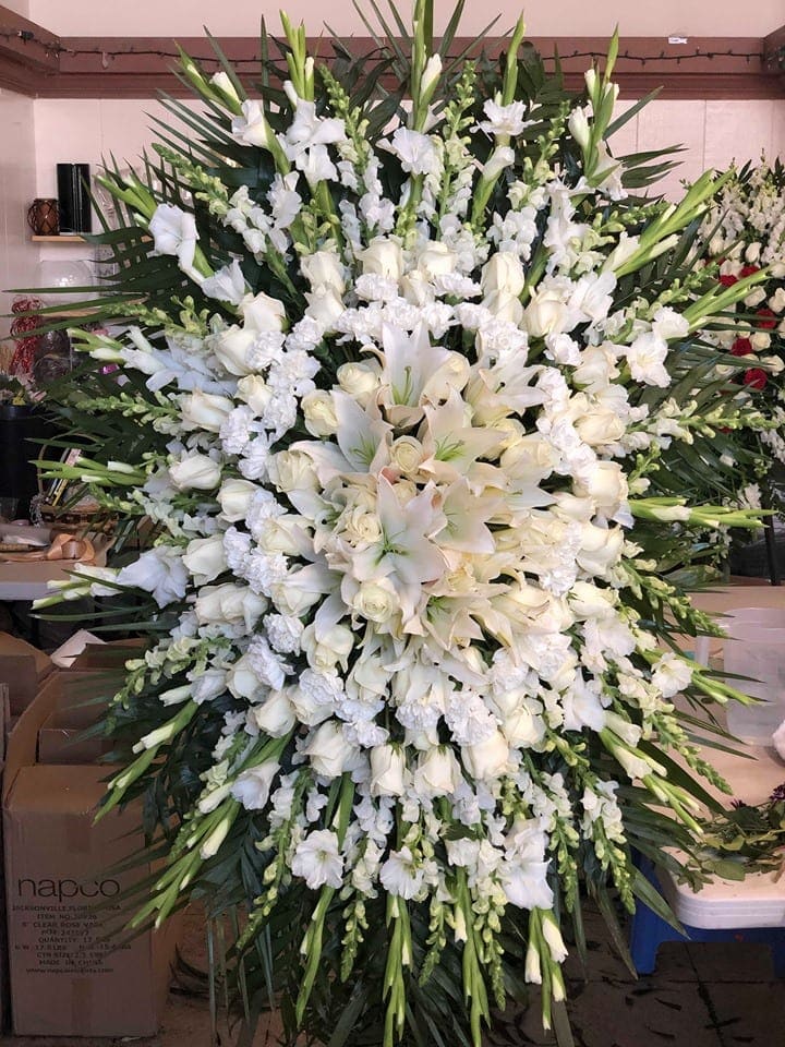 Large white funeral spray with lilies, roses, and orchids