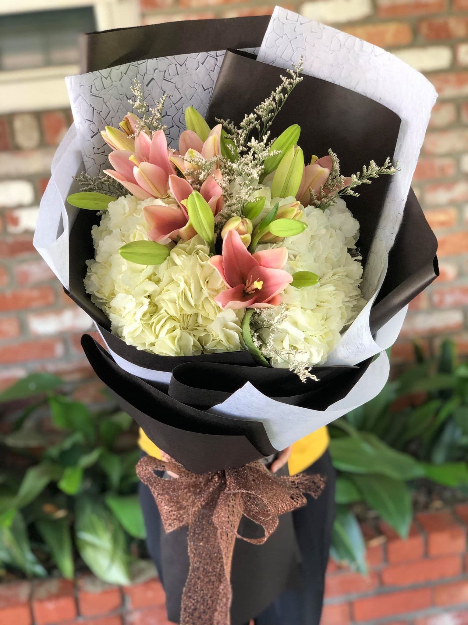Bouquet of pink lilies and white hydrangeas wrapped in black and white paper