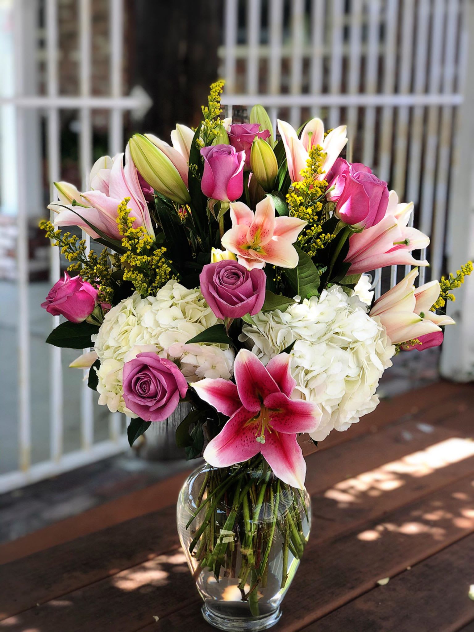 Bouquet of pink lilies, roses, and white hydrangeas in a glass vase