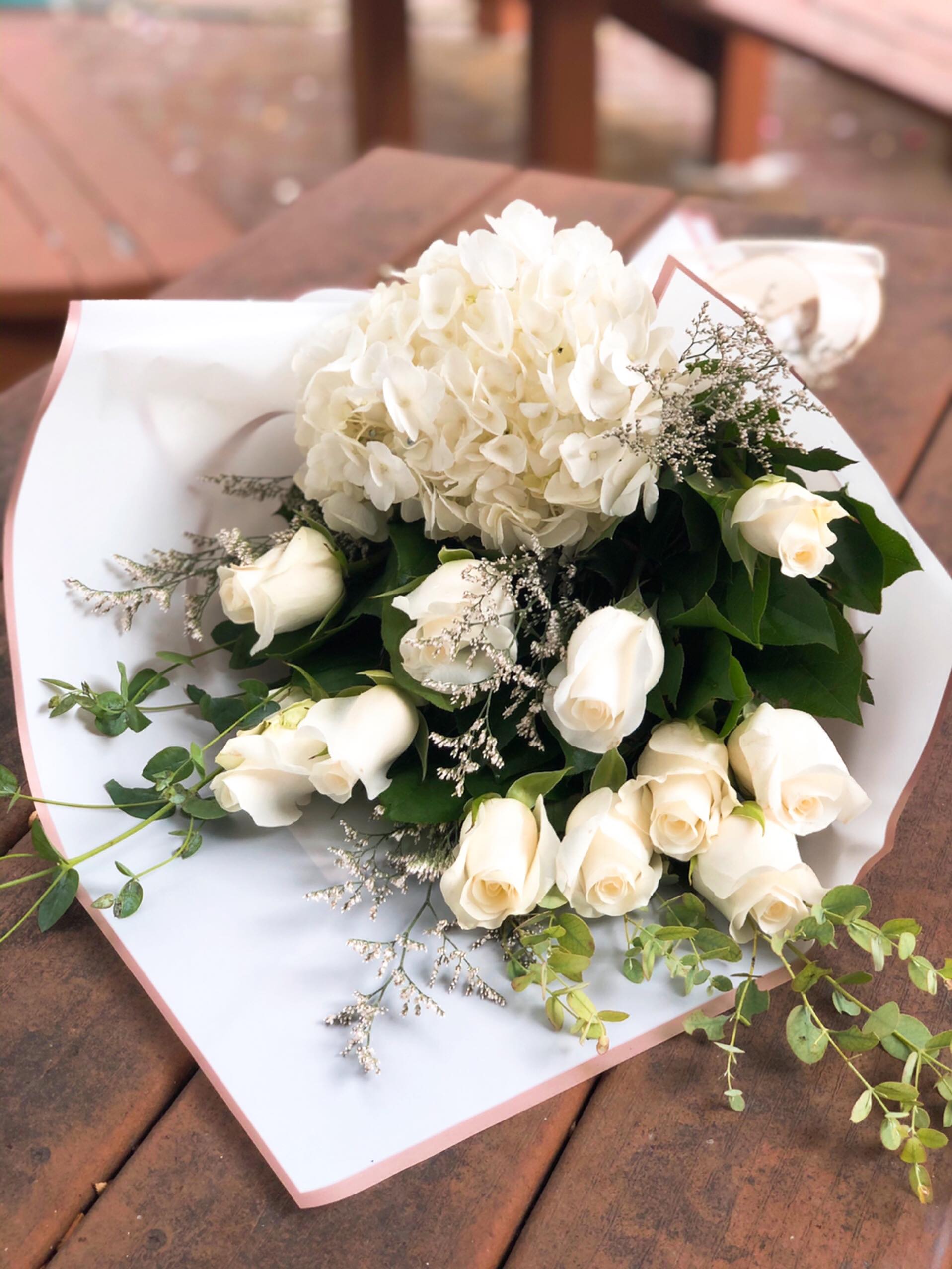 White roses and a white hydrangea bouquet wrapped in white paper