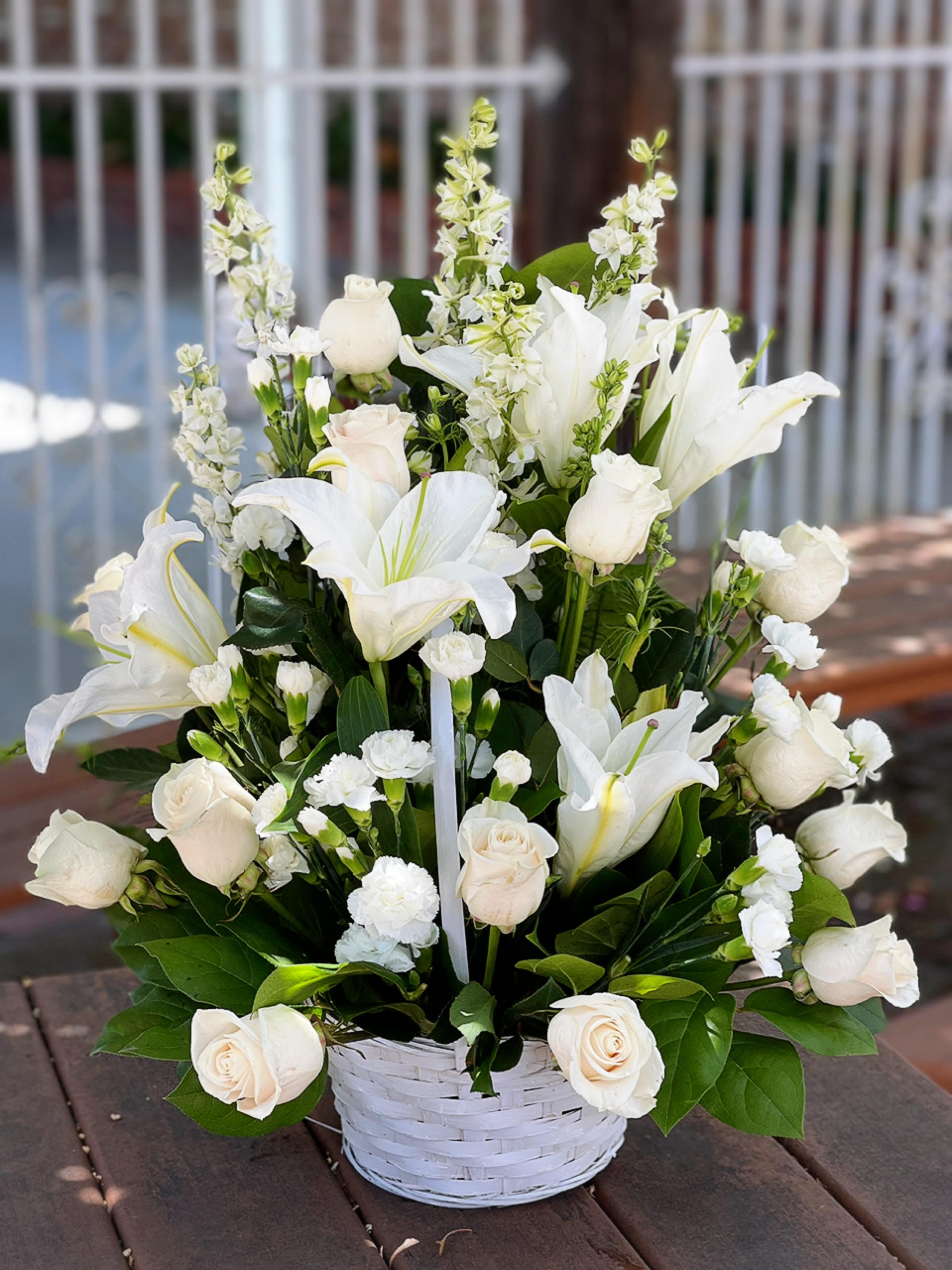 White roses and lilies arranged in a white basket