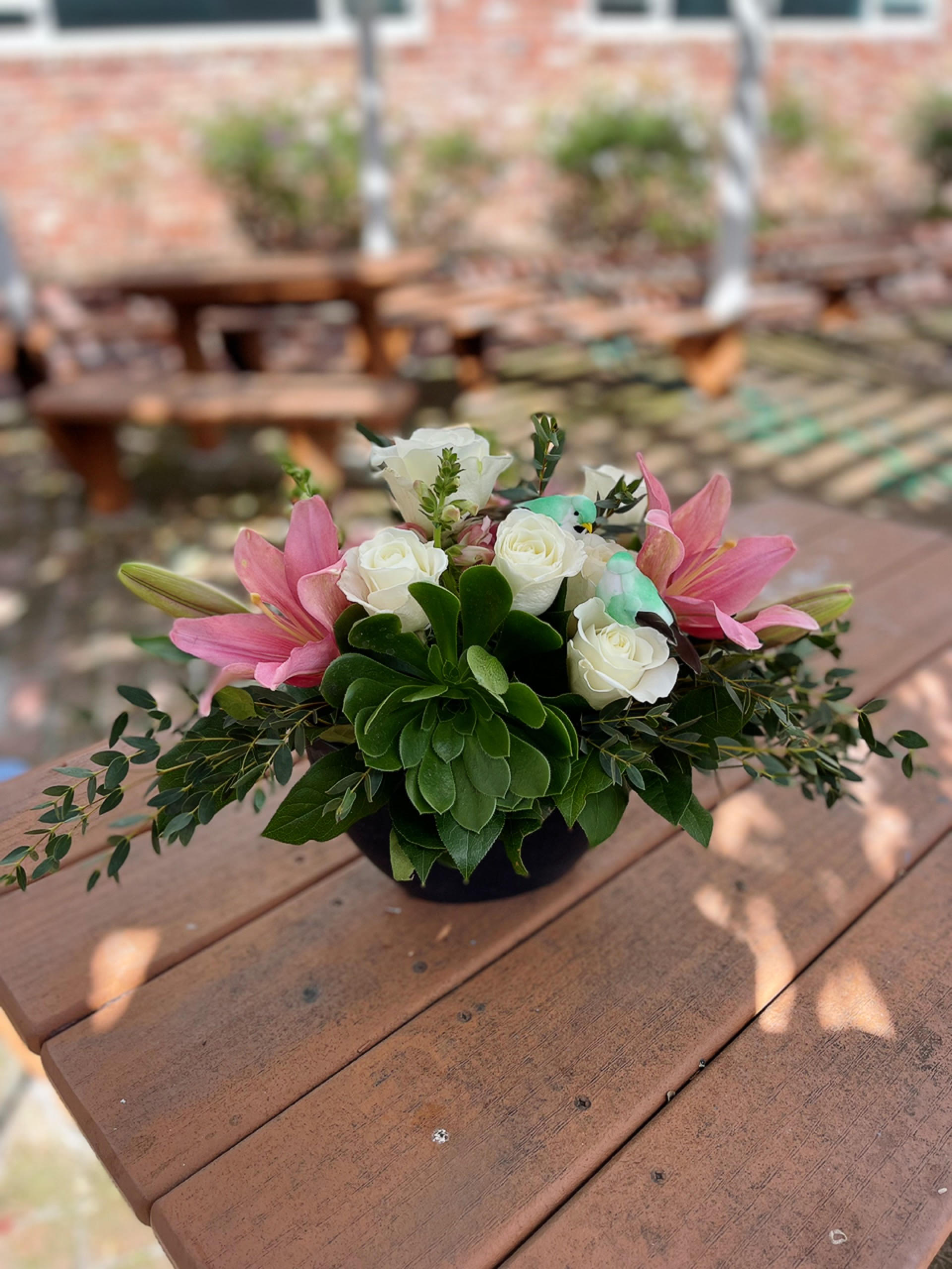 Pink lilies and white roses in a low black container