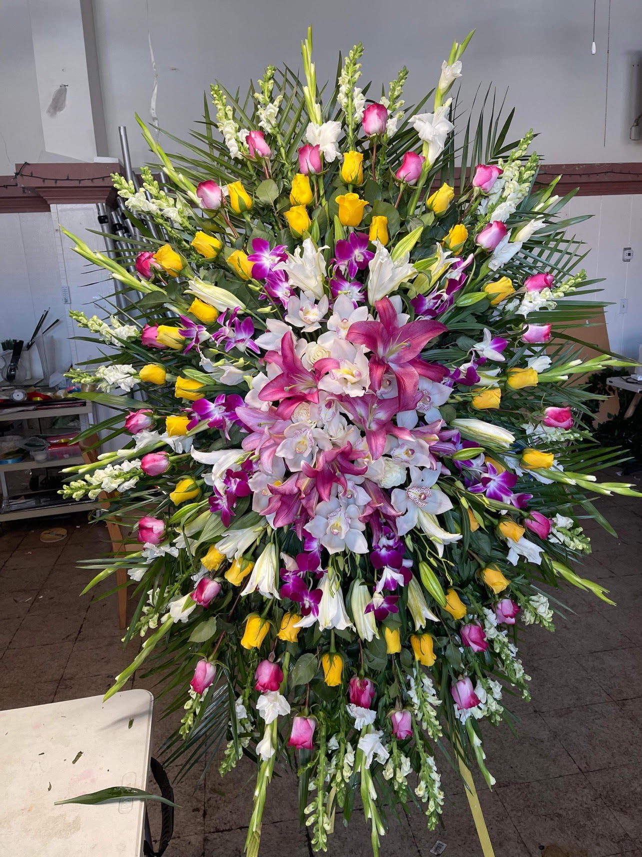 Large standing floral spray with pink, yellow, white, and purple blooms
