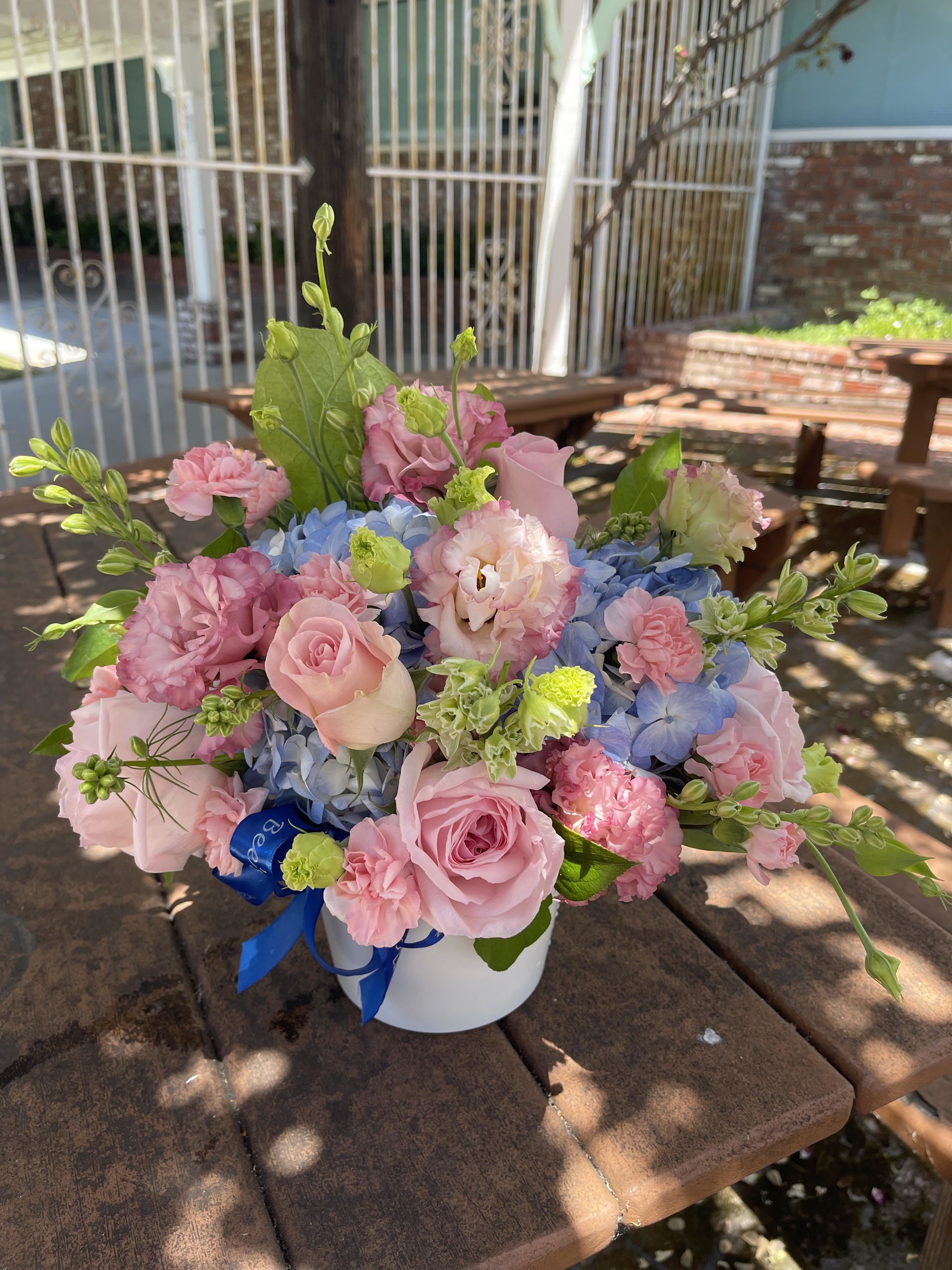 made for mom  - Soft pink roses and ruffled carnations pair with clusters of blue hydrangea and pale lisianthus to create a garden-fresh bouquet made for mom - ideal as a Mother's Day gift, a birthday surprise, or a spring anniversary celebration. The pastel palette reads romantic and cheerful, the mix of rounded hydrangea clusters and delicate lisianthus buds giving the arrangement a soft, textured presence that will make the person you're thinking of feel truly seen and celebrated.