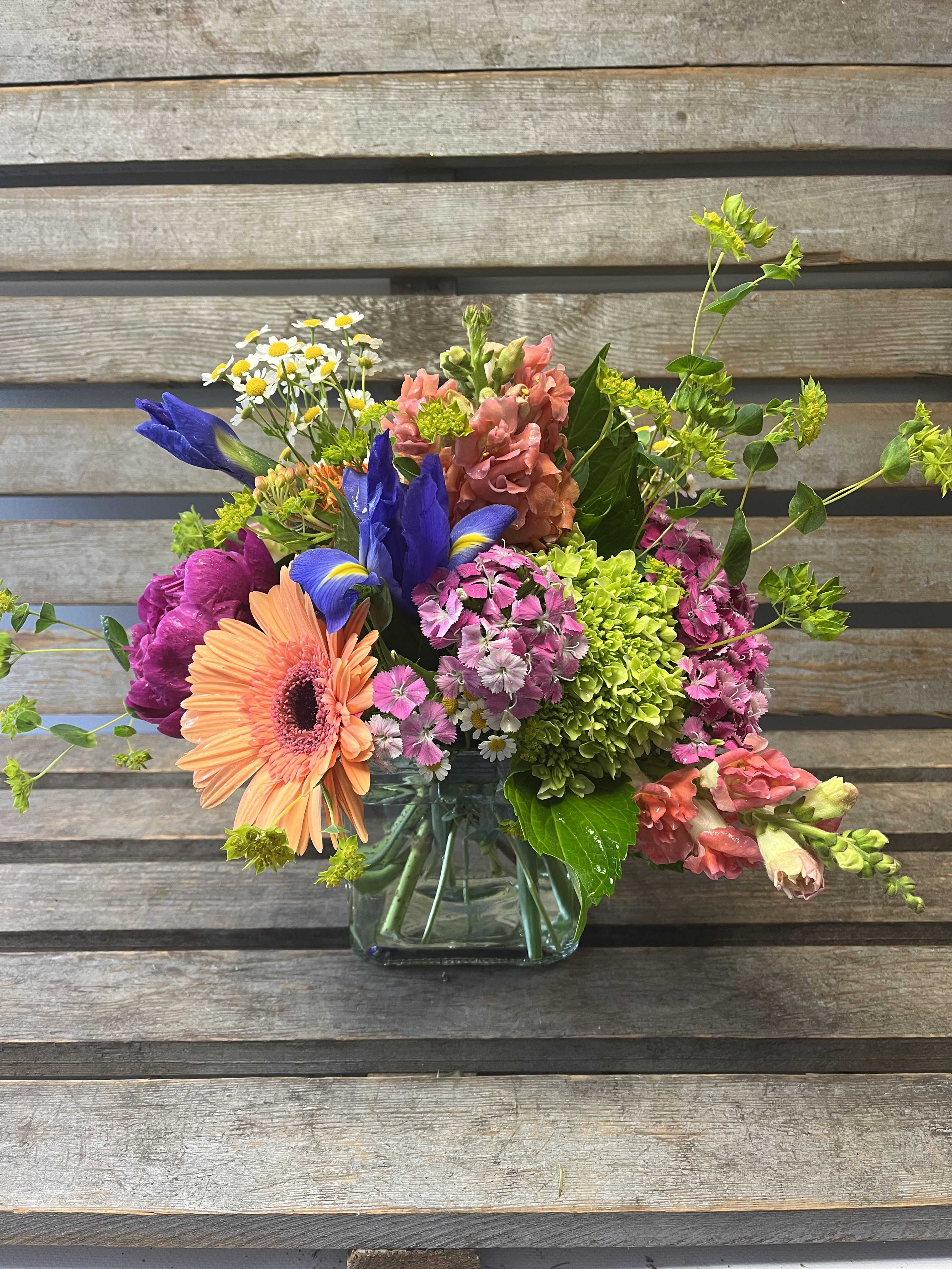 Colorful mixed bouquet in a clear glass vase with gerbera, iris, and hydrangea
