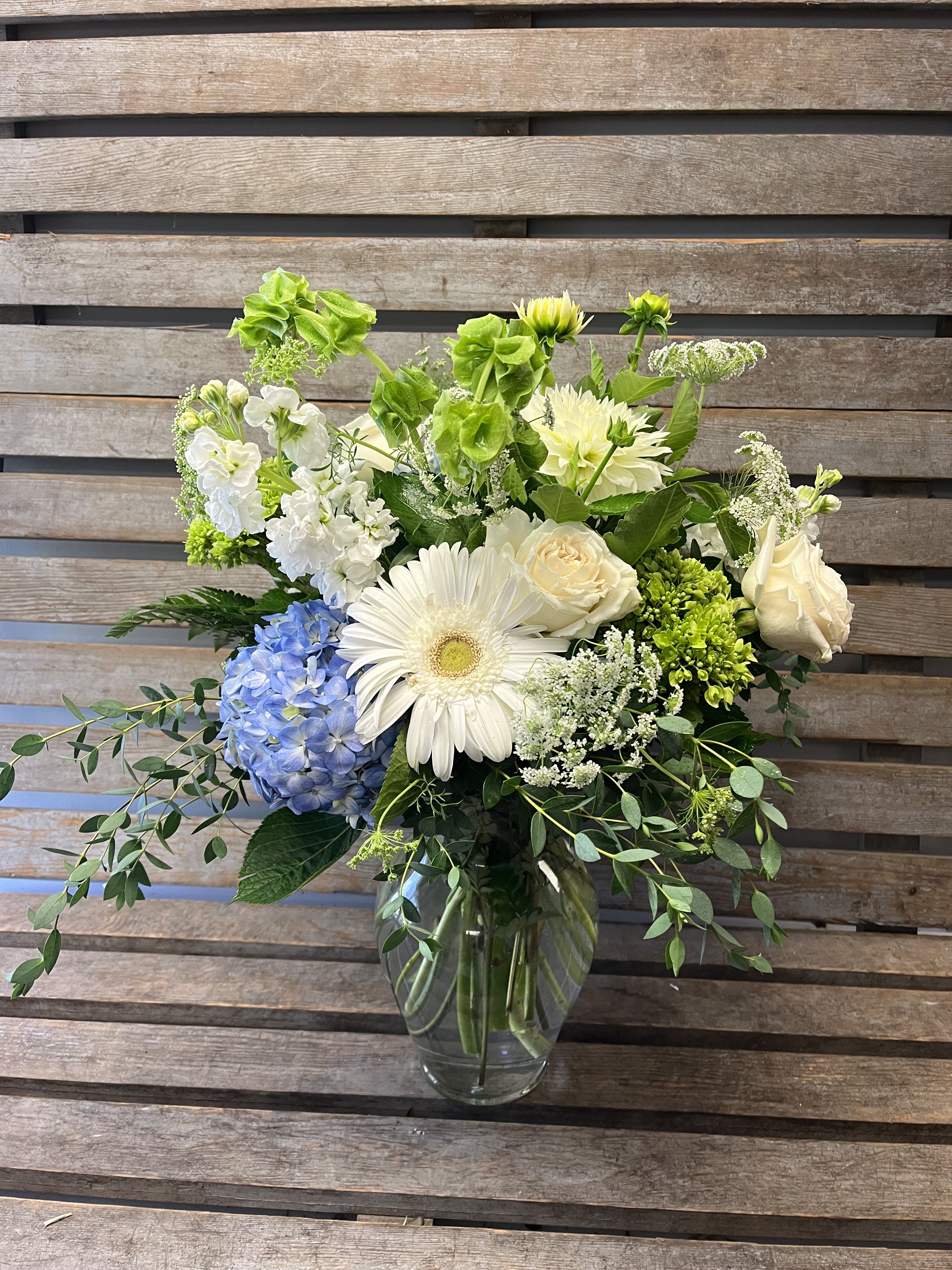 Mixed white and blue flowers arranged in a clear glass vase