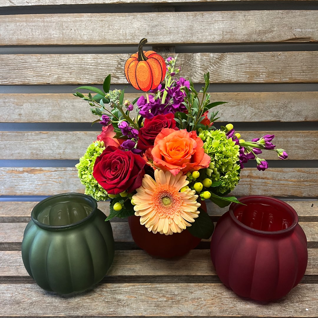Fall bouquet with roses, gerbera daisy, and purple blooms in a pumpkin container