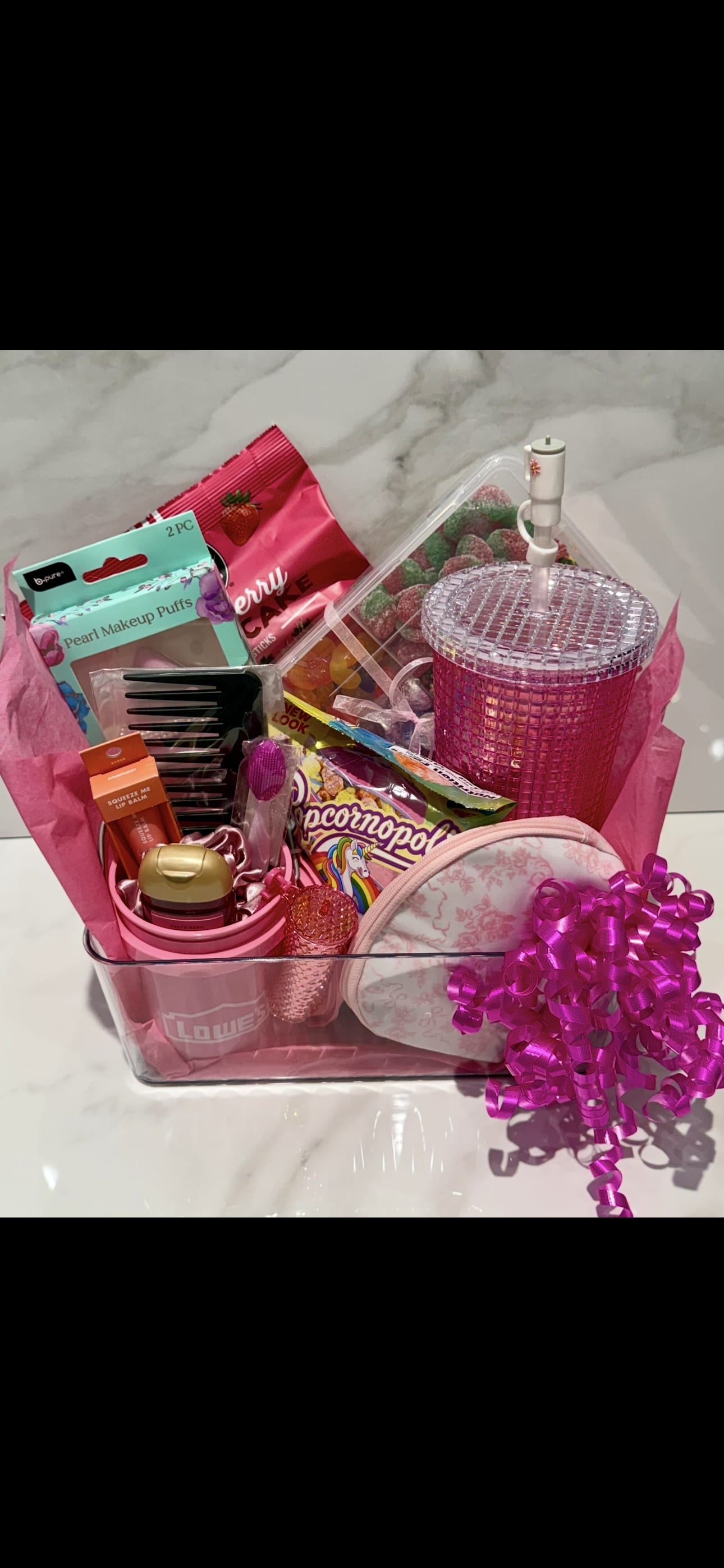Pink gift basket with candy, makeup items, and a glittery tumbler