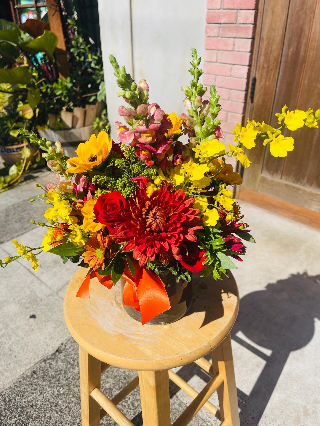 Bright mixed bouquet in a glass vase with red, yellow, and orange flowers
