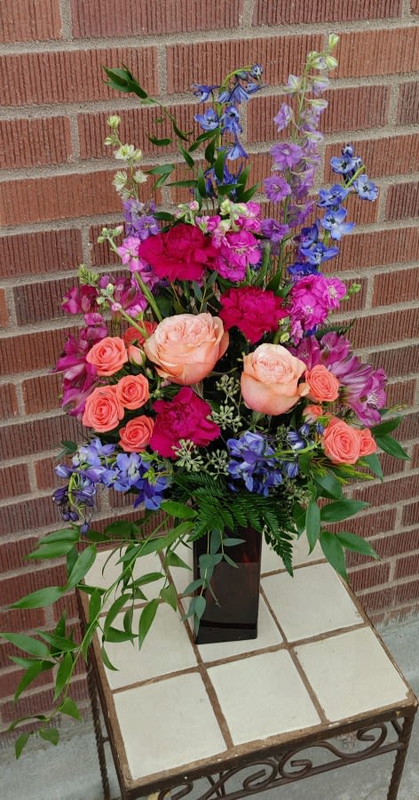Tall mixed bouquet with pink roses and purple-blue flowers in a black vase