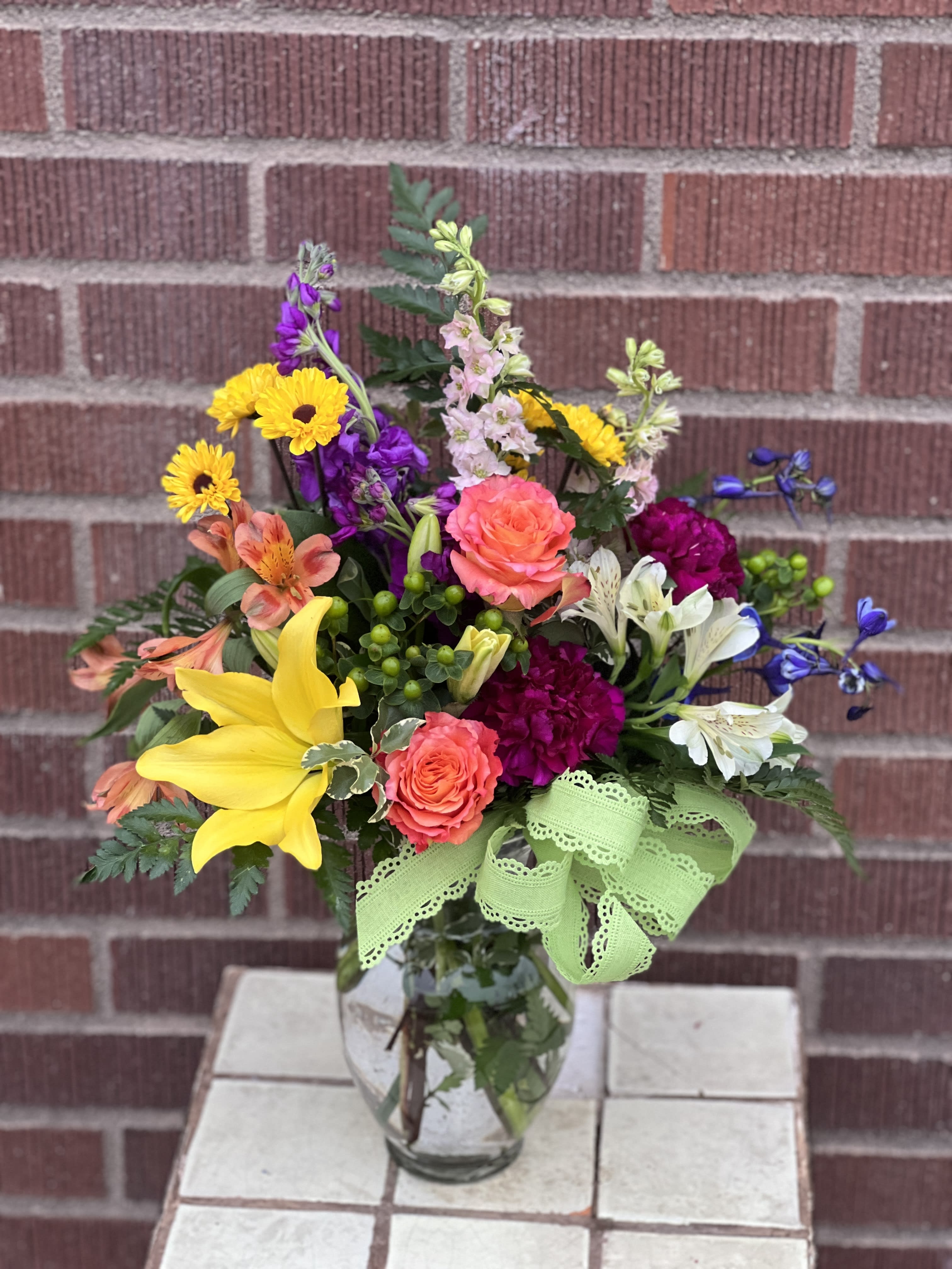 Mixed bouquet in a glass vase with yellow lilies and bright roses