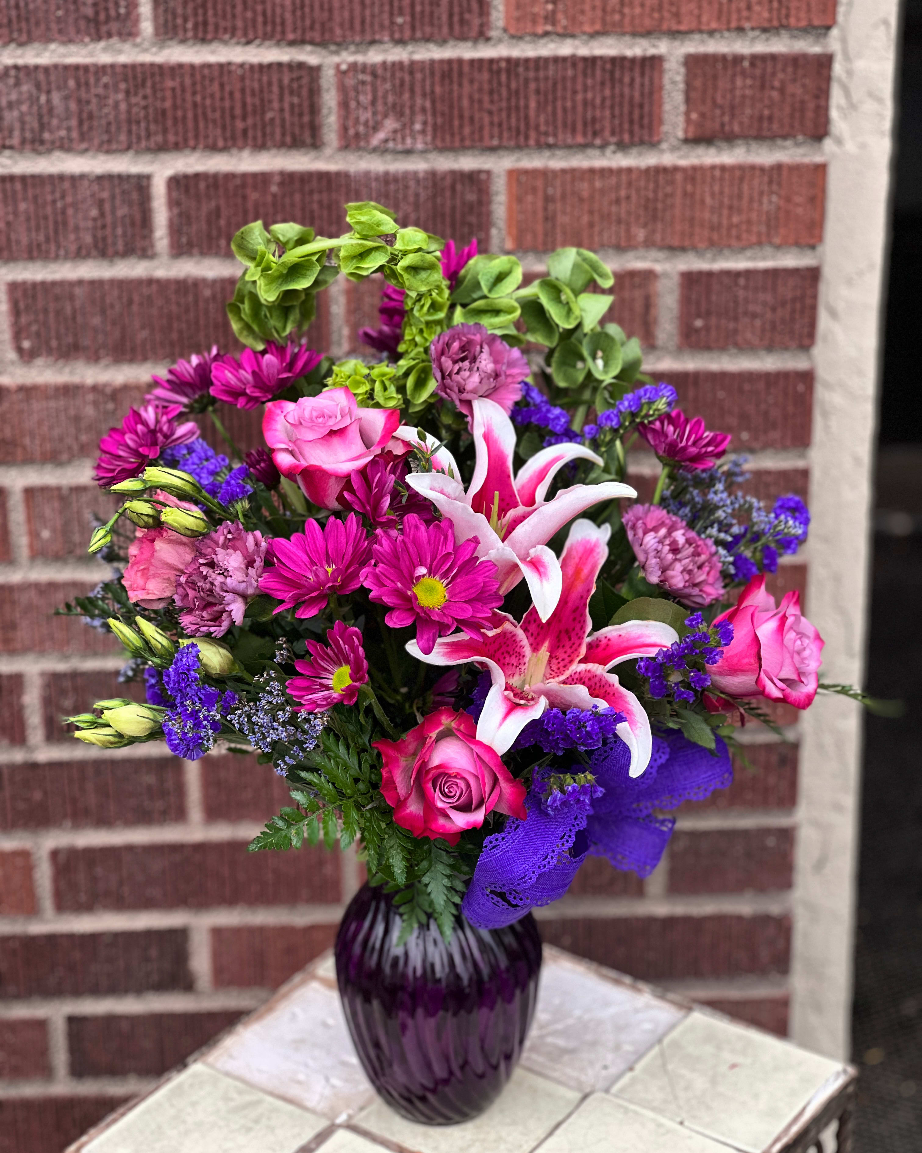 Pink and purple bouquet with lilies and roses in a purple vase