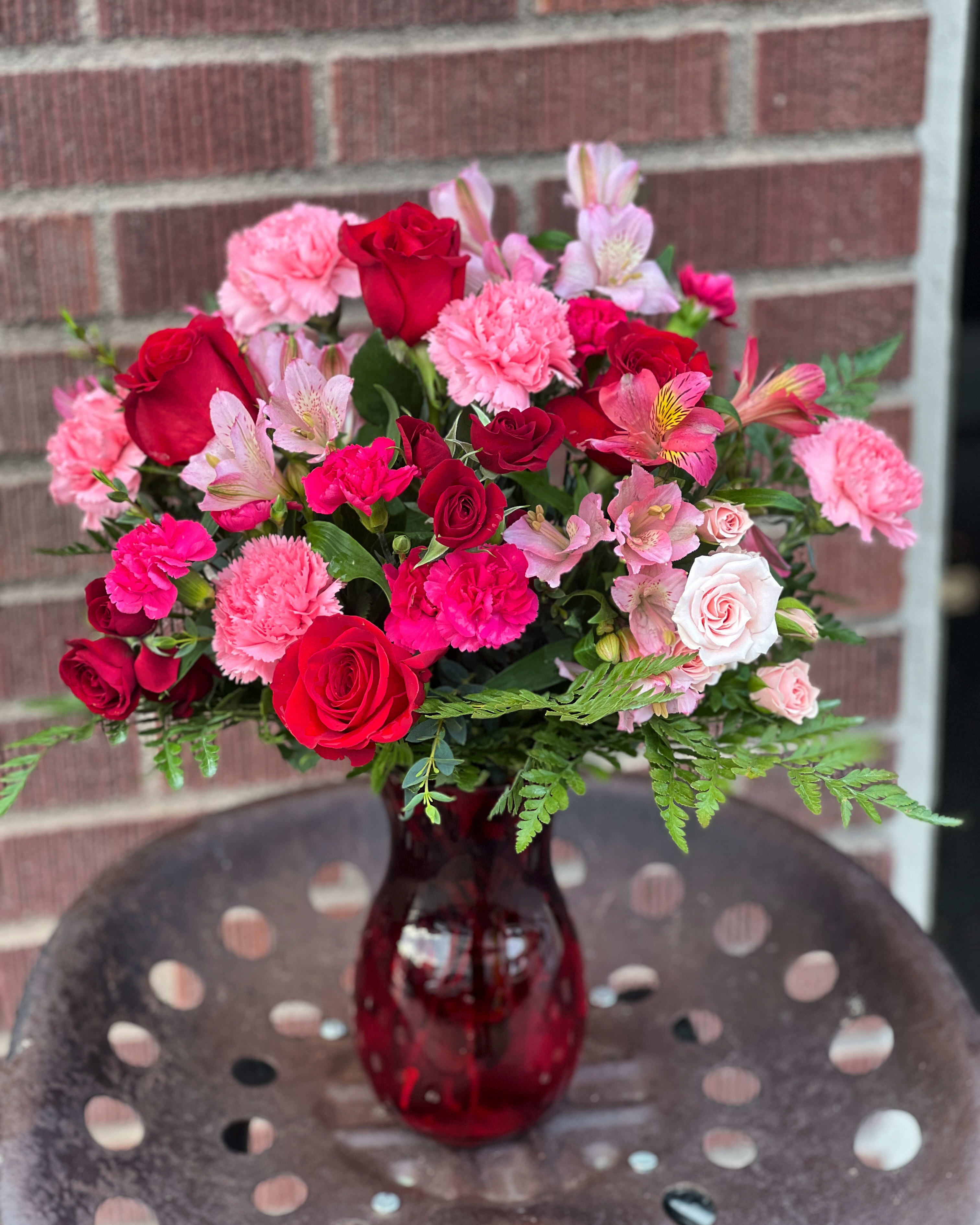 Bouquet of red and pink flowers in a red glass vase