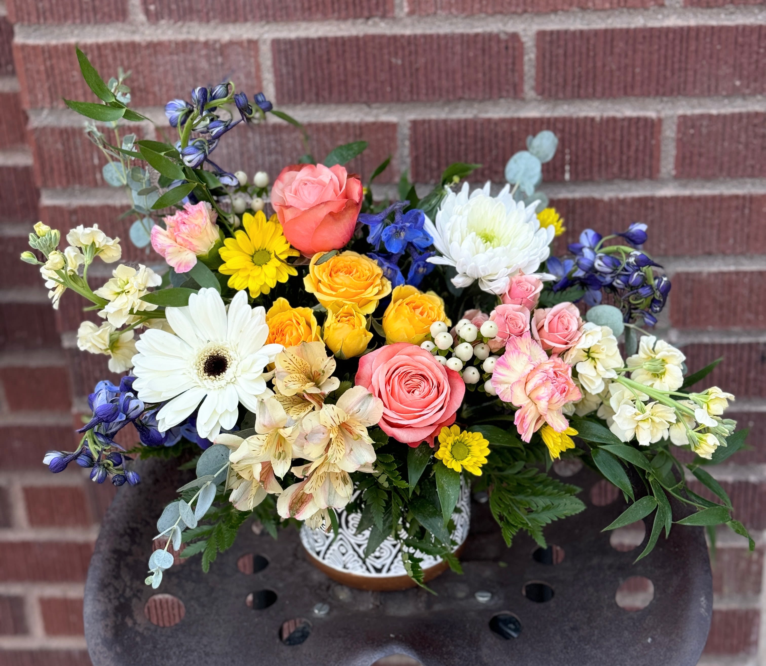 Mixed bouquet of roses, daisies, and white chrysanthemums in a decorative vase