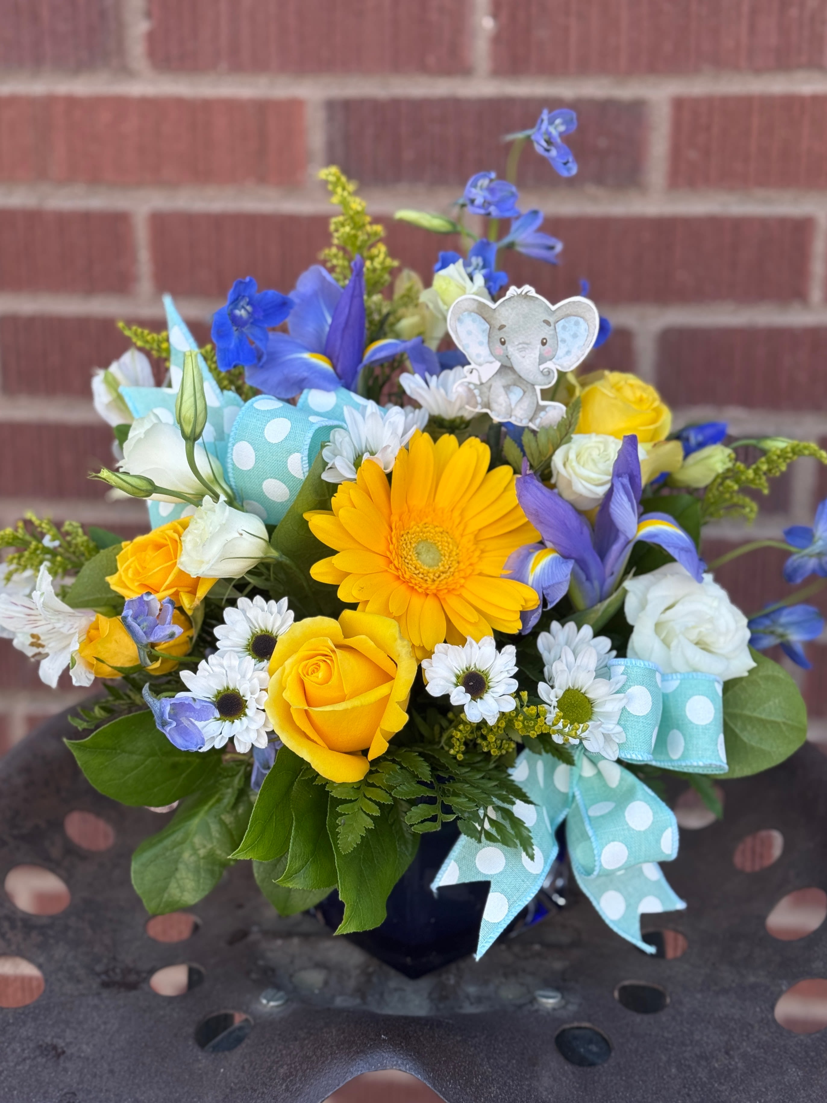 Yellow and white bouquet with blue flowers and a baby elephant pick