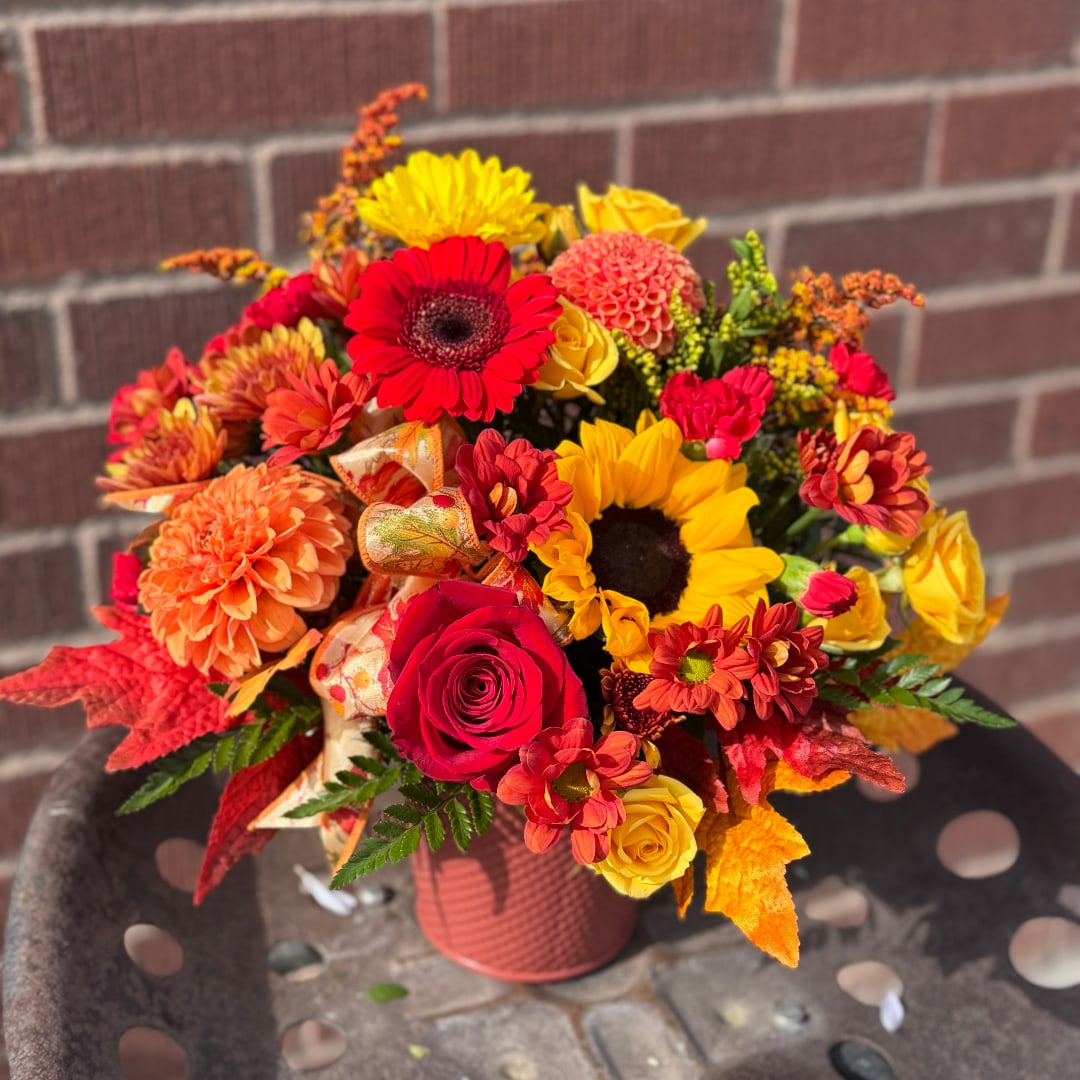 Autumn bouquet with red, yellow, and orange flowers in a pink vase