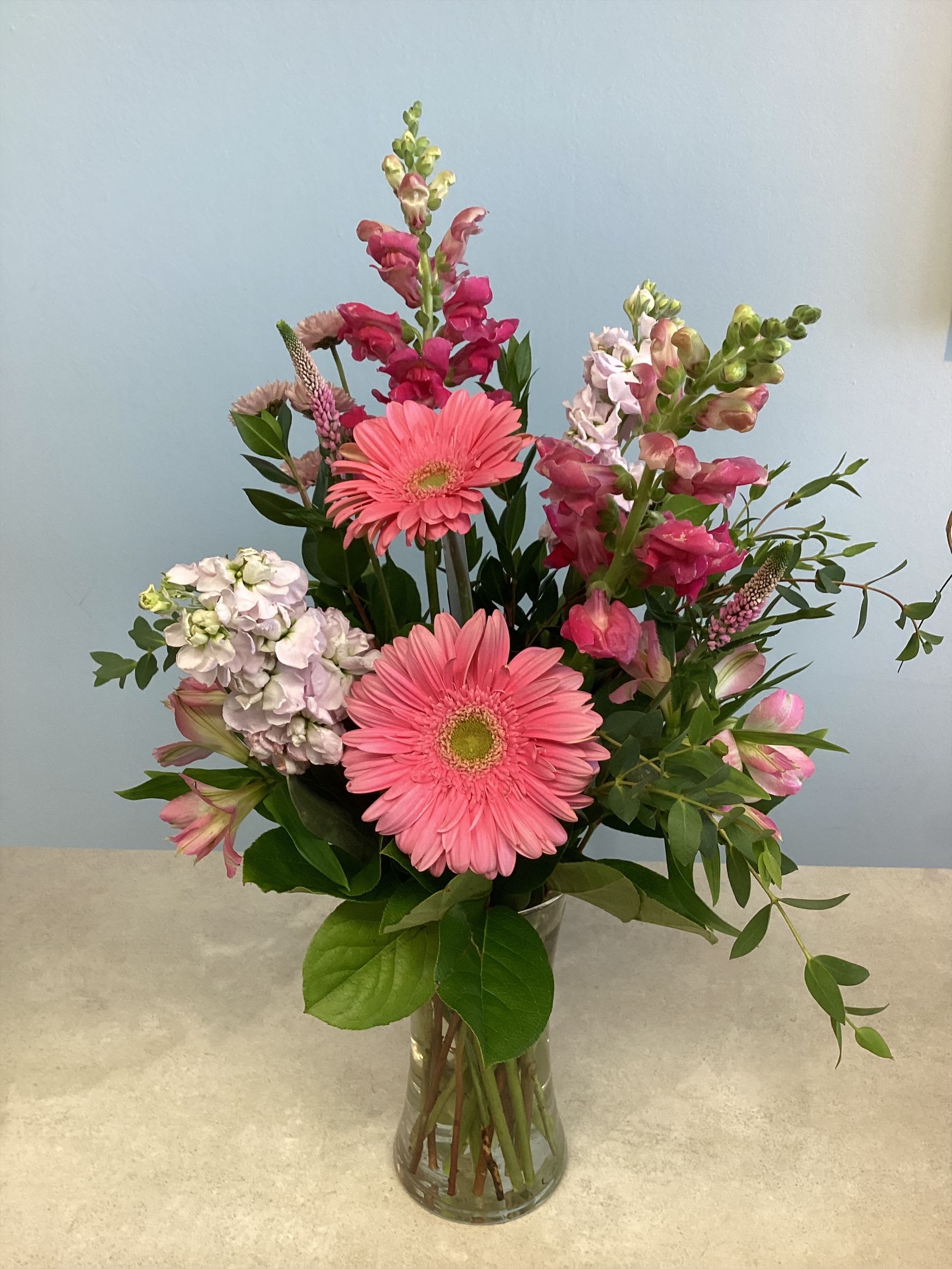 Pretty in Pink - A lovey arrangement for pink lovers! Spring flowers in shades of pink to include snapdragons, stock, gerbera daisies and fillers.