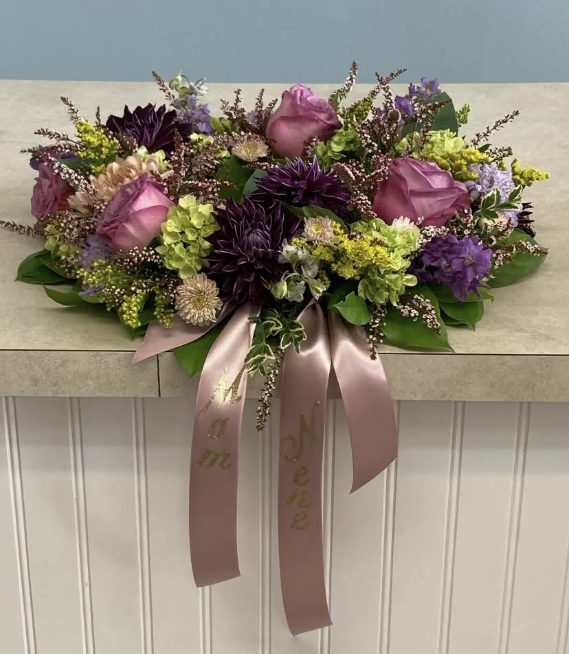 Sympathy Urn Wreath #3 - Lavender roses, purple dahlias, stock blooms, green hydrangeas and mums with accents of solidago and calycina, arranged in a compact garden-style urn wreath, finished with a dusty rose satin ribbon for a warm, elegant tribute.