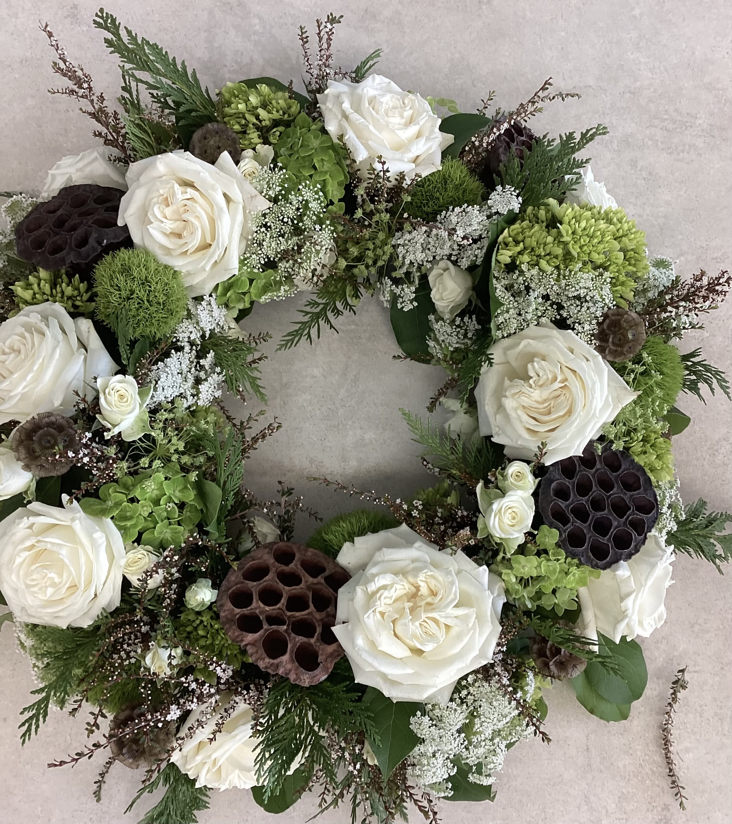 Woodland Oasis Sympathy Urn - Honor your loved one with this organic, natural, woodsy style urn wreath composed of white roses, green hydrangeas and lotus pods with textured greenery accents. 
