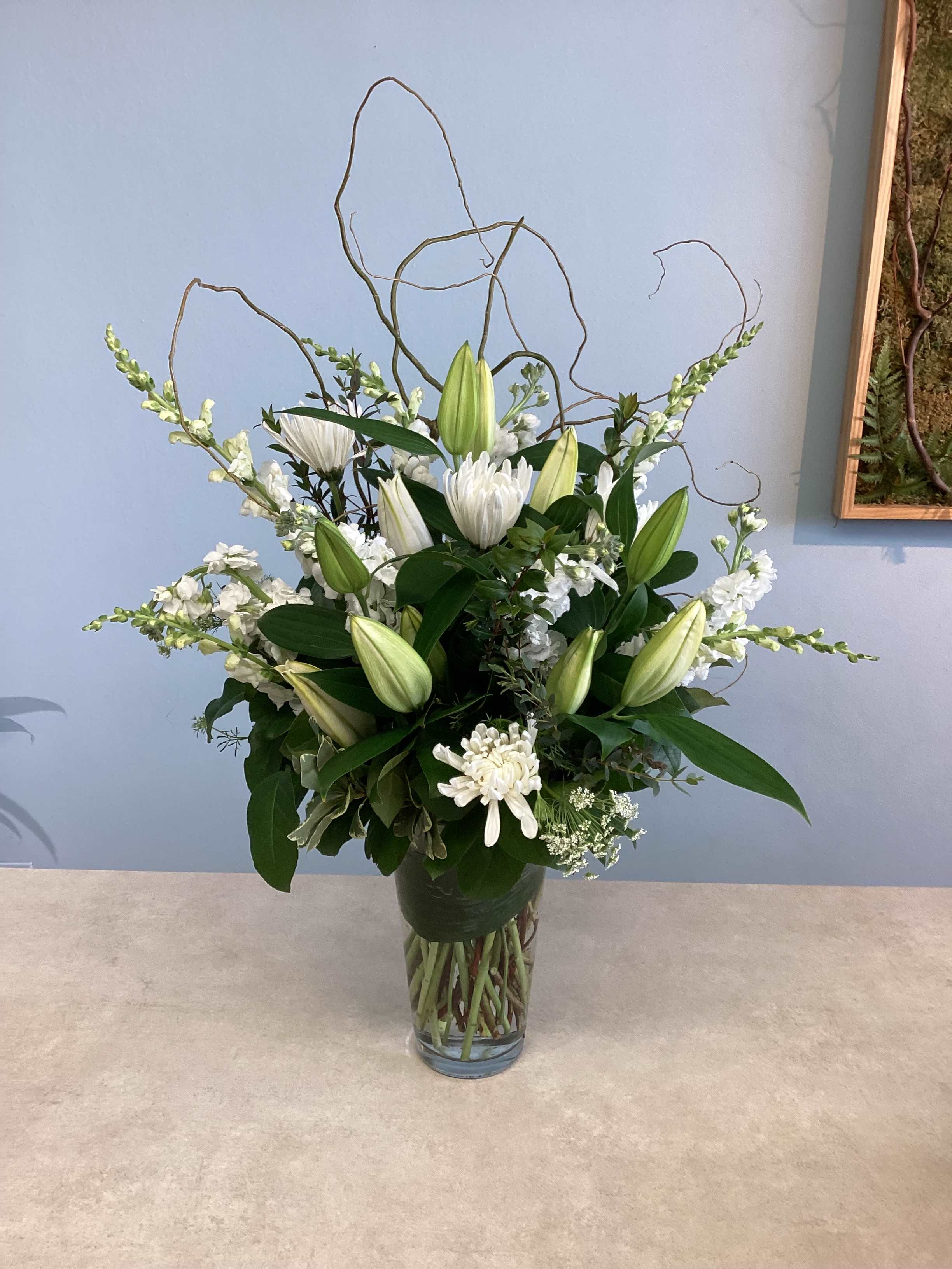 White lilies and chrysanthemums arranged in a clear glass vase