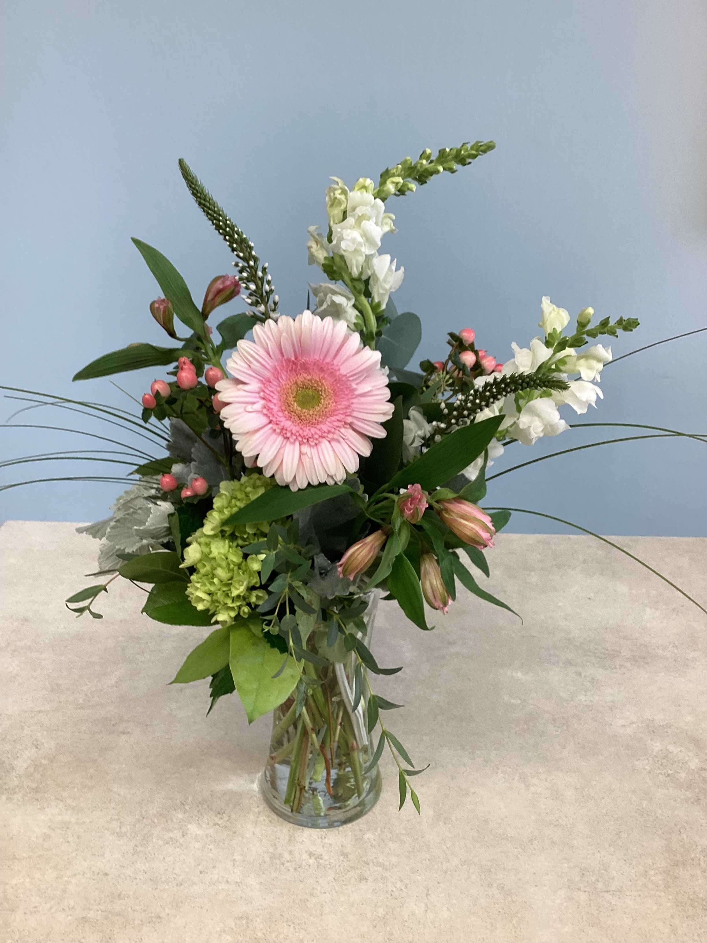 Pink gerbera daisy arrangement in a clear glass vase with white blooms