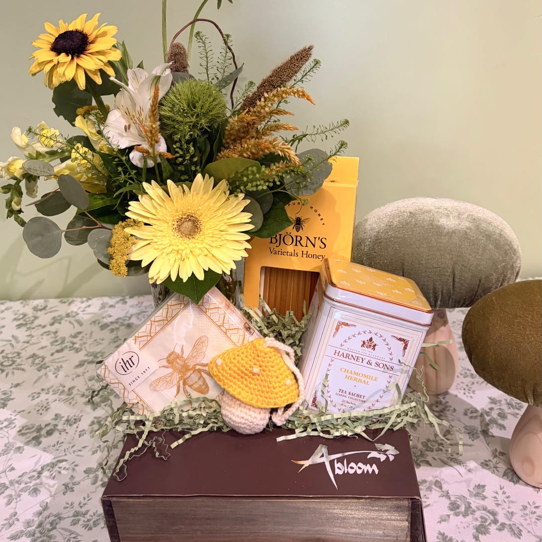 Mixed flower bouquet with honey and tea gift items in a box