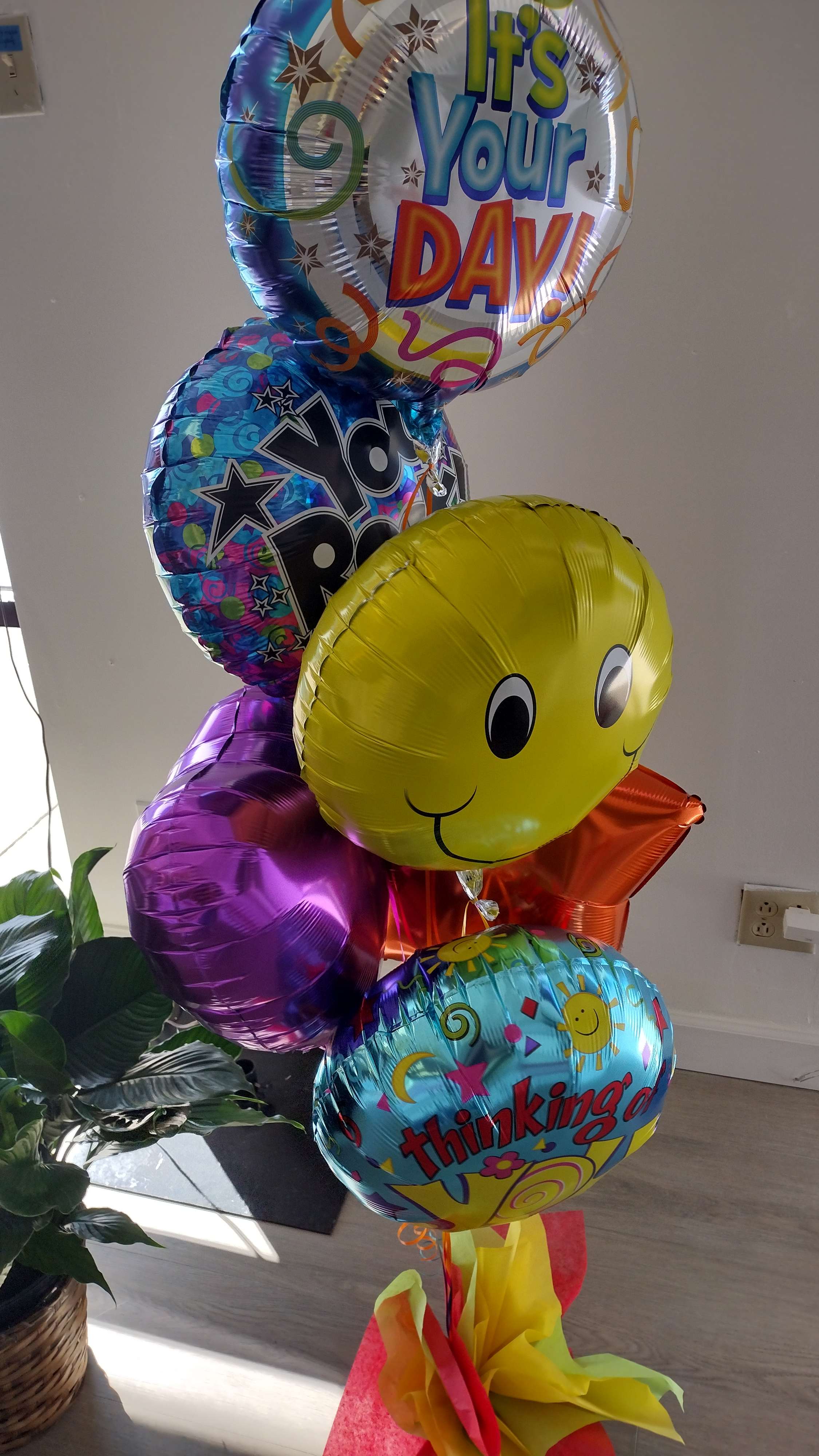 Cluster of colorful birthday balloons with smiley faces and text