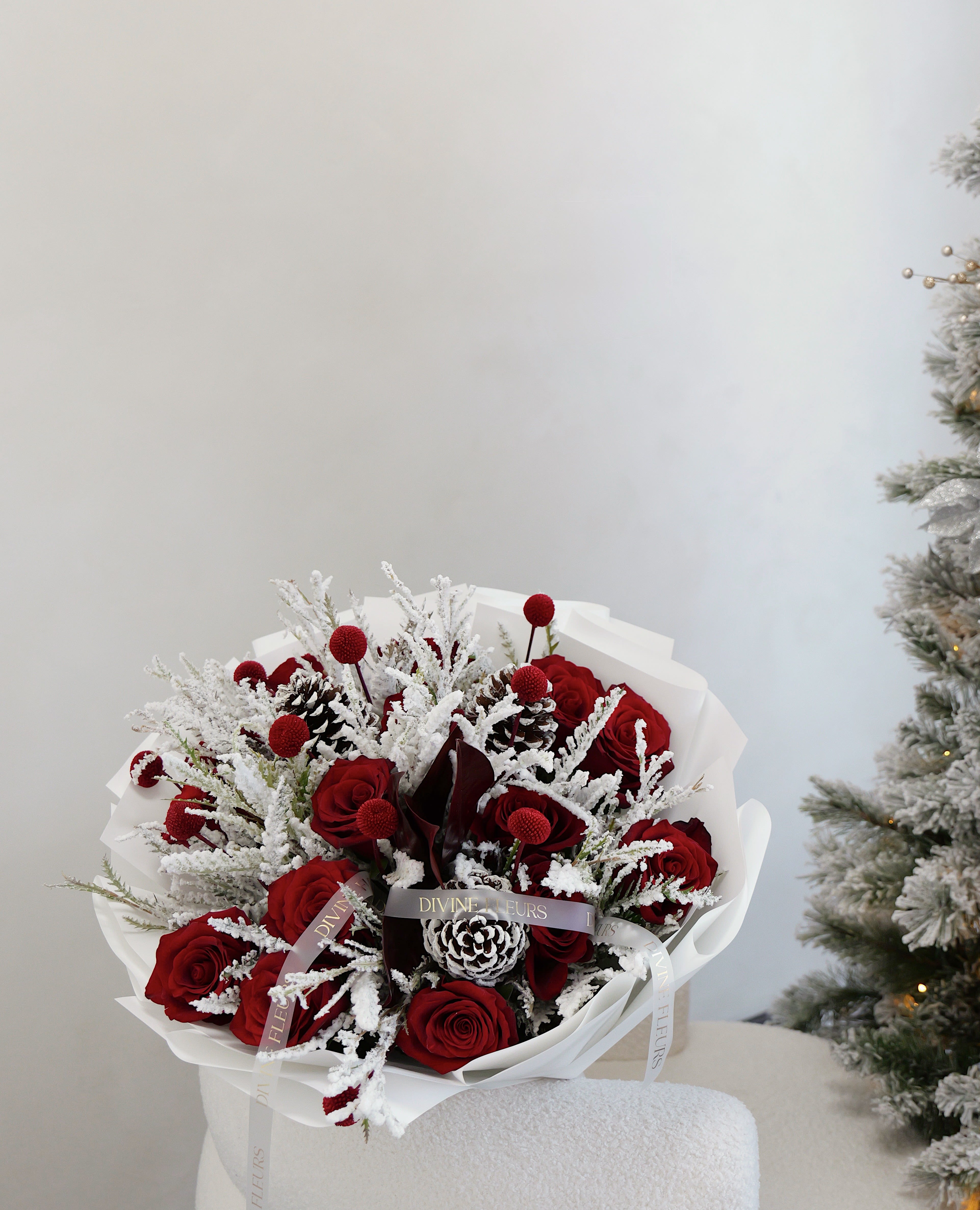 Bouquet of red roses with frosted white accents and pinecones