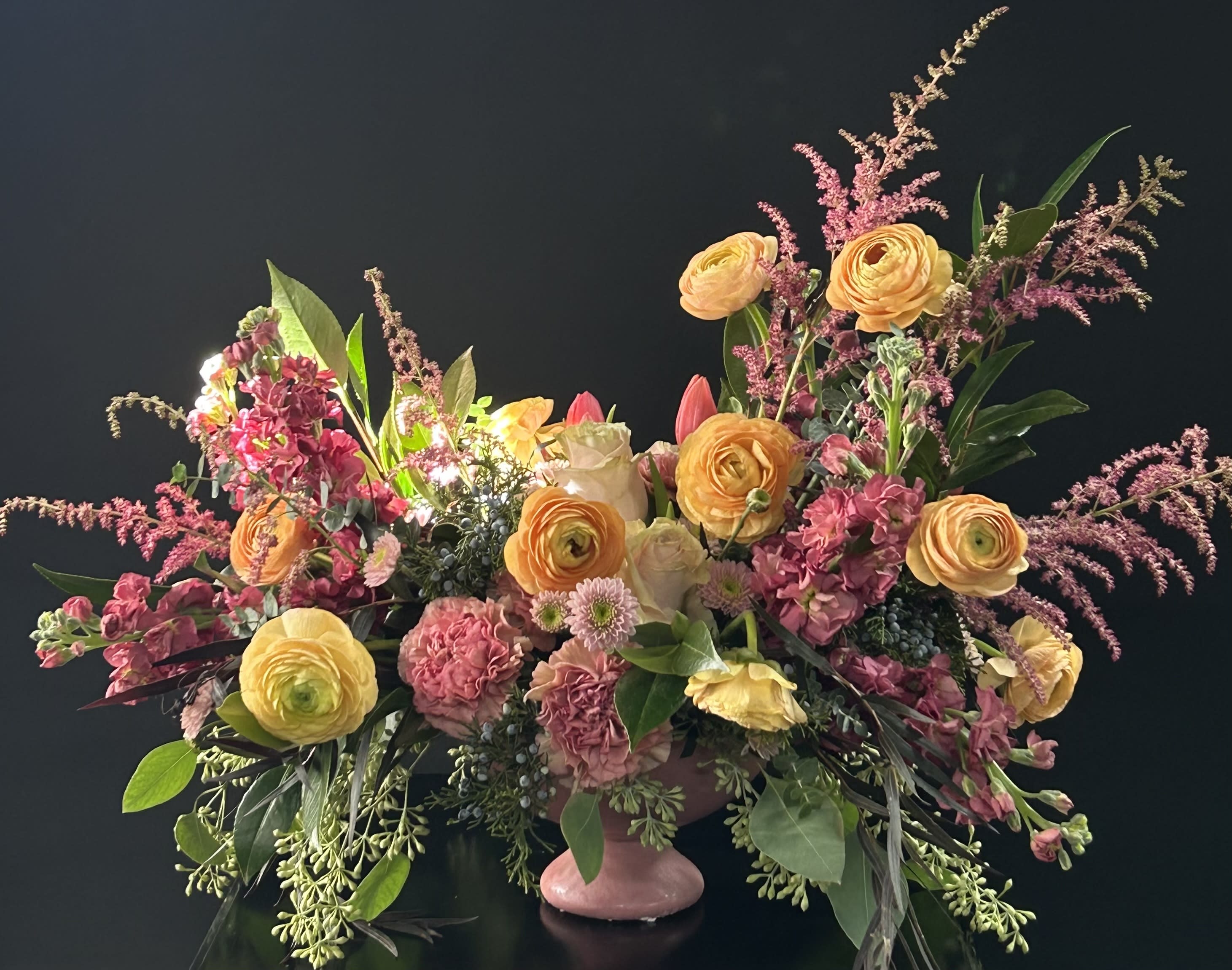 Large mixed floral arrangement in a pink pedestal vase