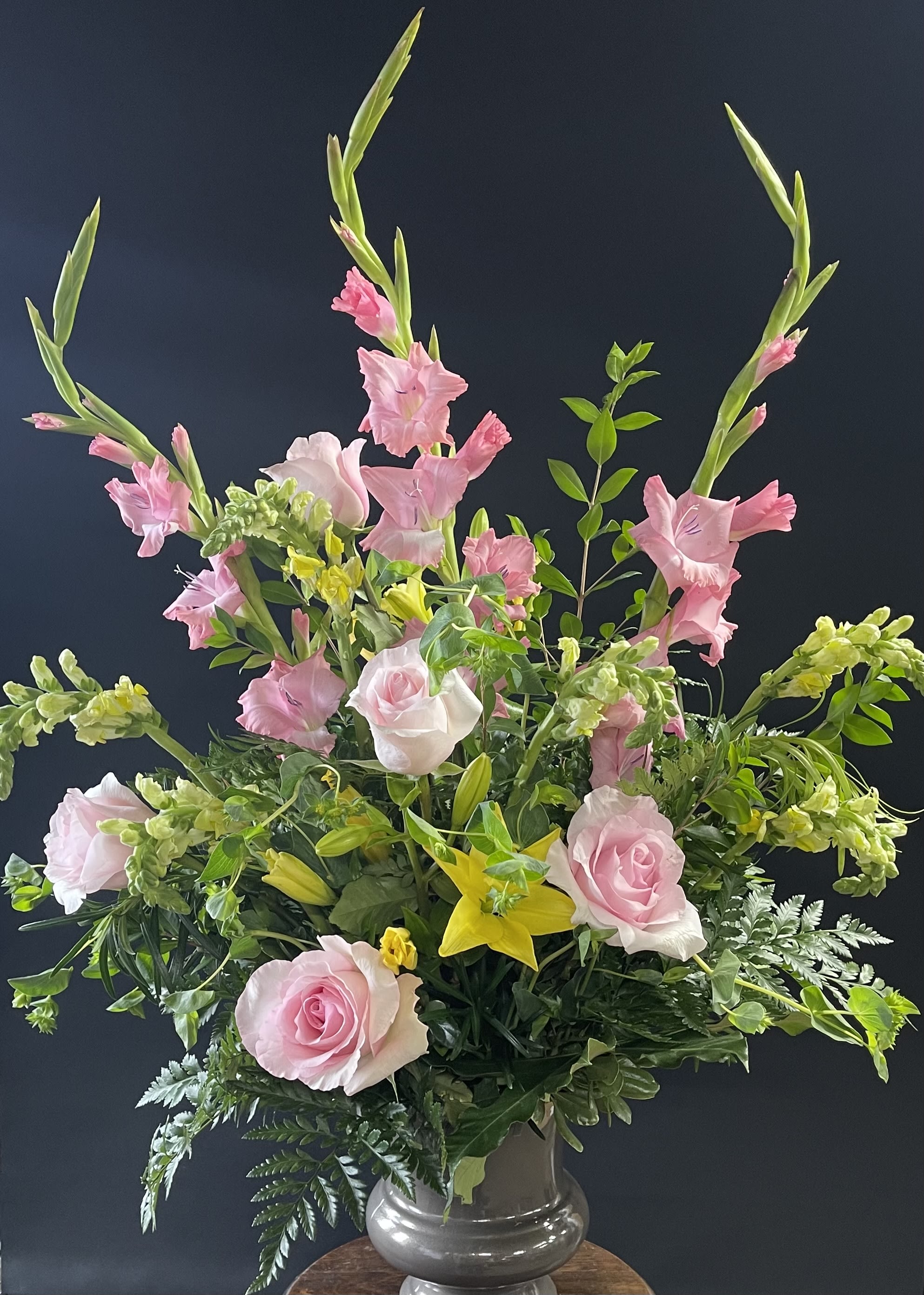 Pink roses and gladiolus in a glass vase with yellow lilies