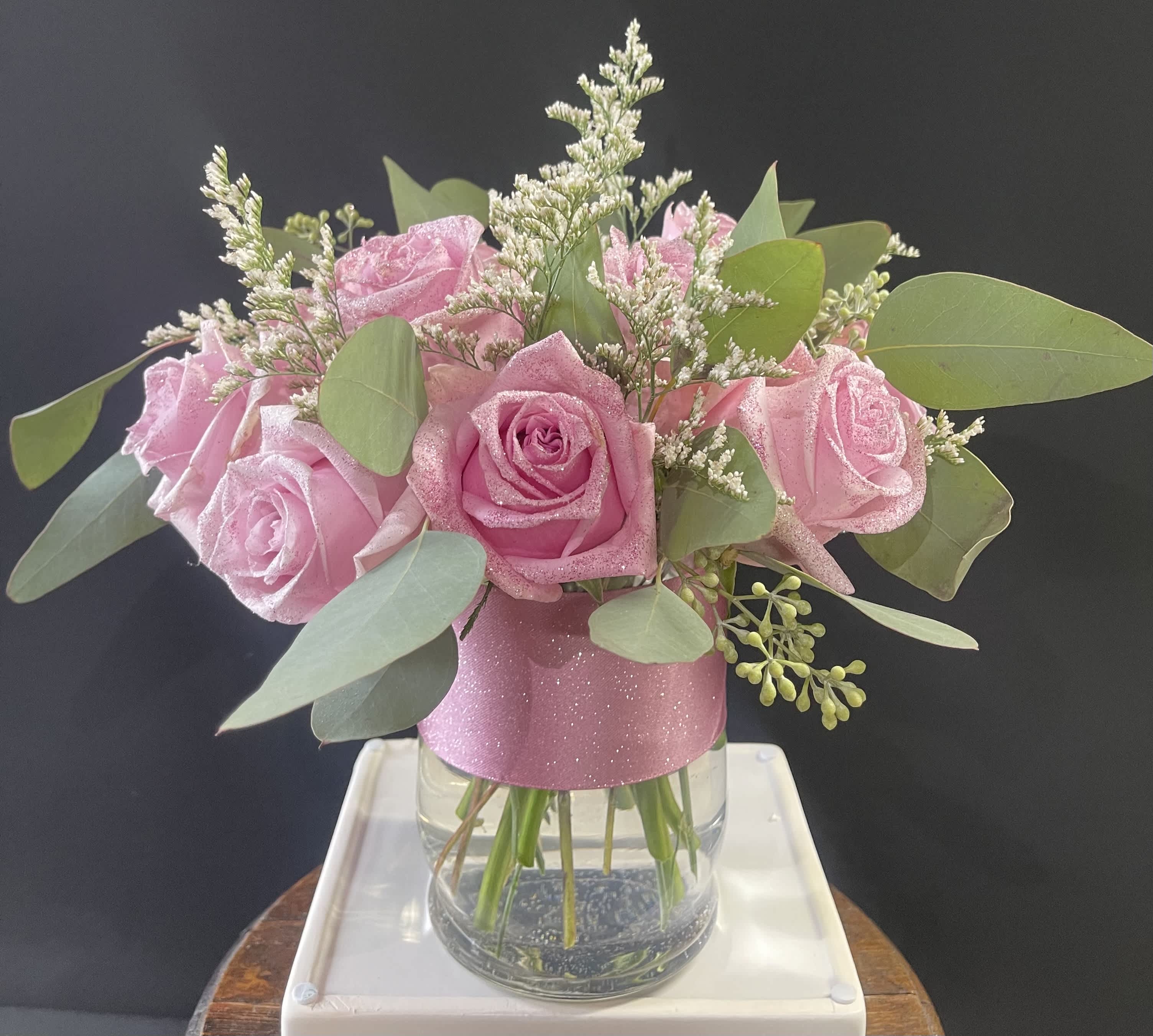 Pink roses in a clear glass vase with eucalyptus and filler flowers