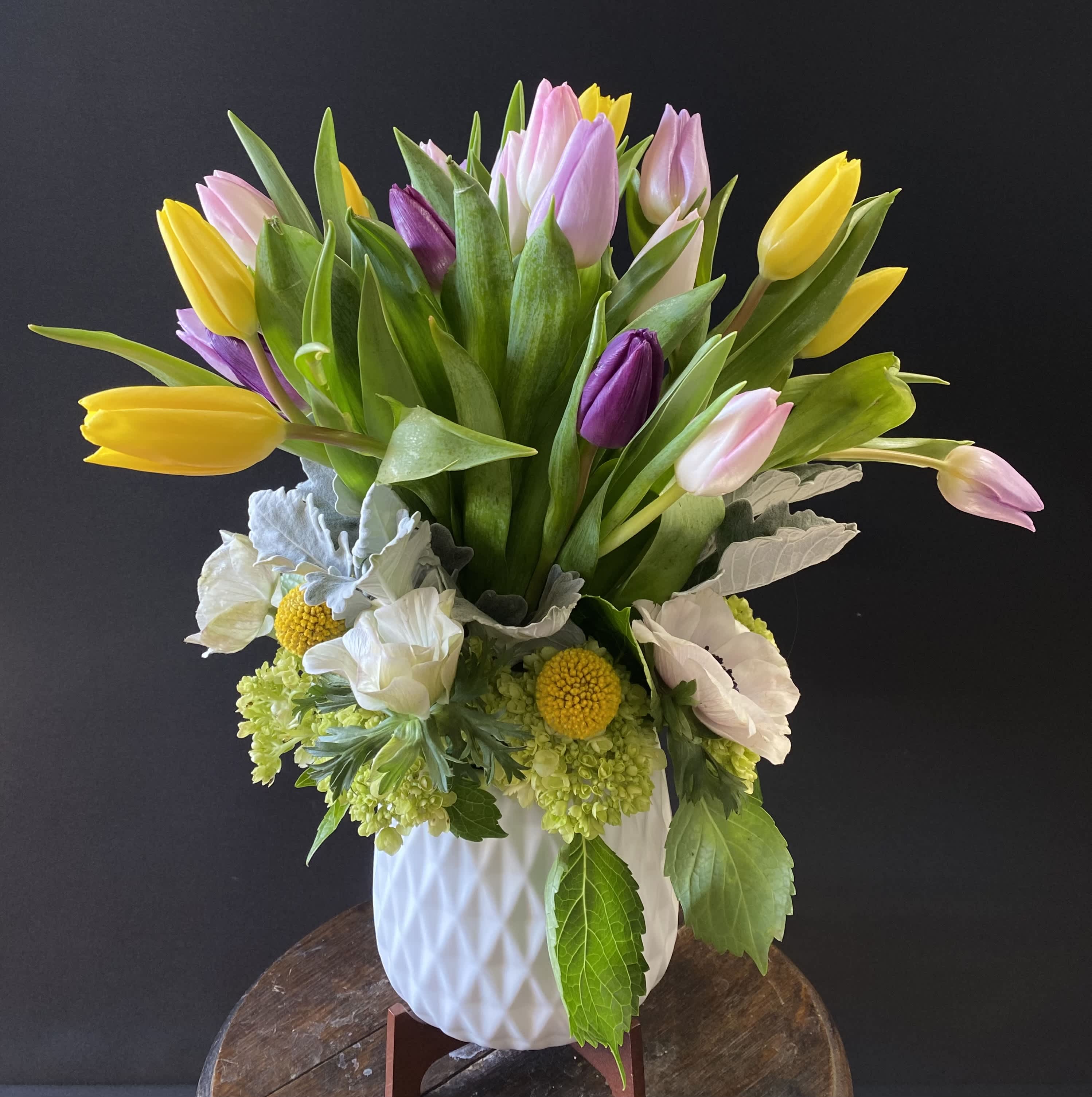 Bouquet of yellow, pink, and purple tulips in a white vase