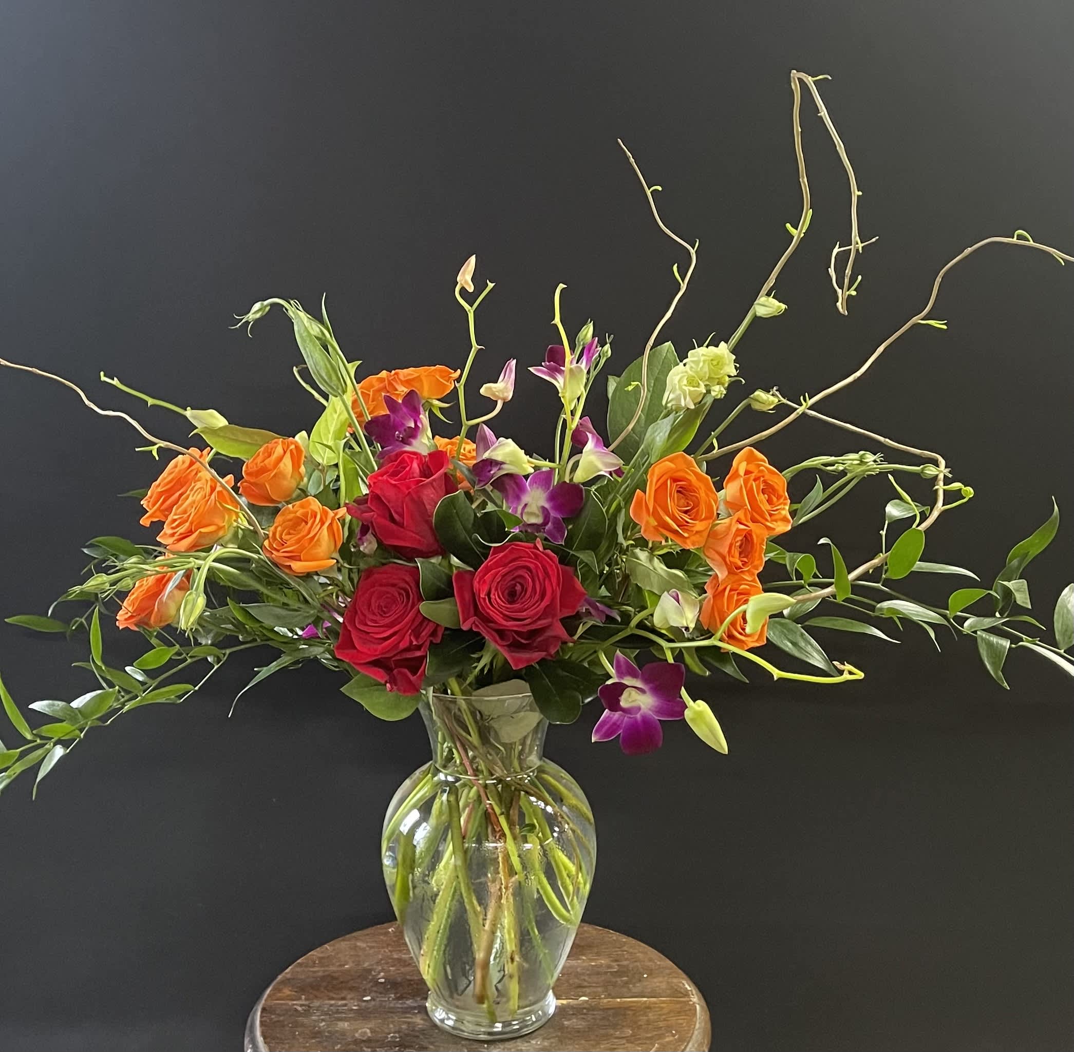 Mixed roses and orchids in a clear glass vase