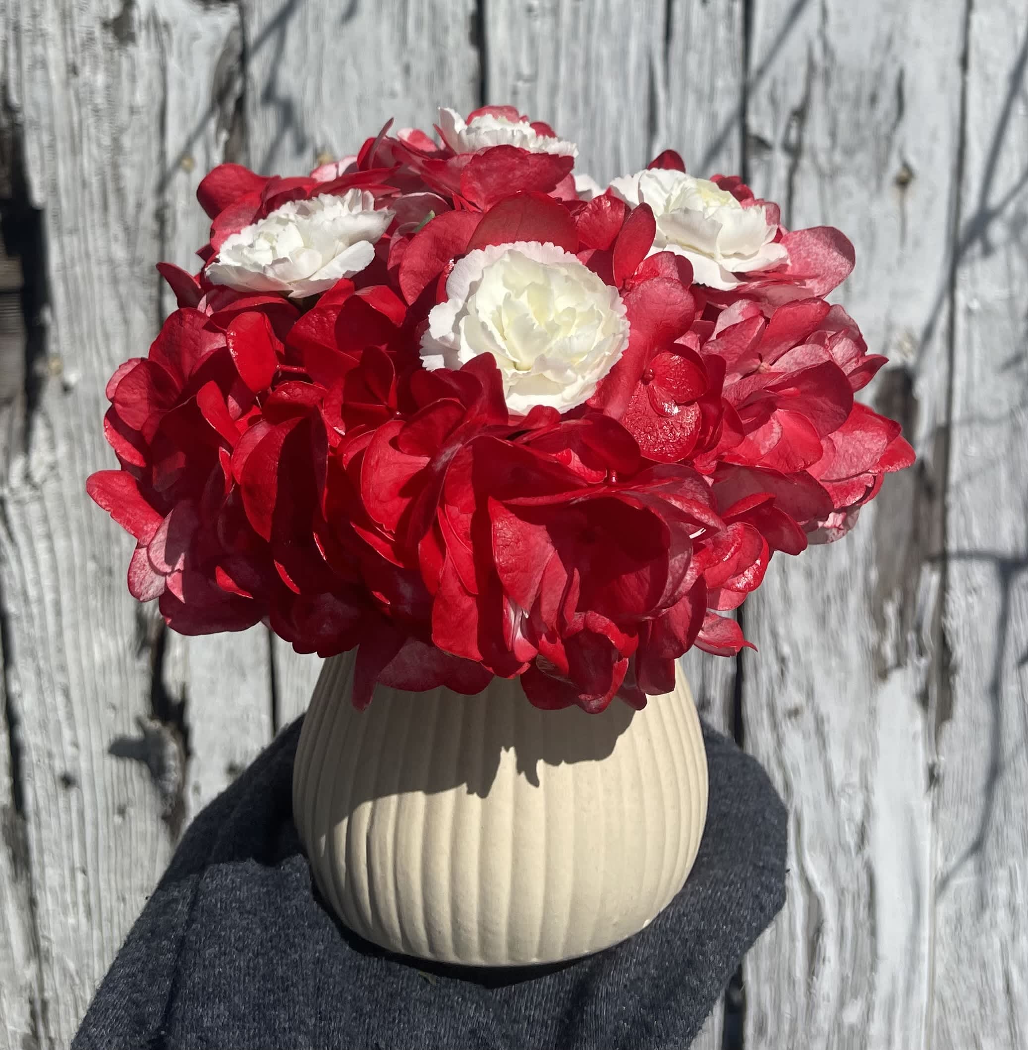 Red and white flower arrangement in a beige ribbed vase