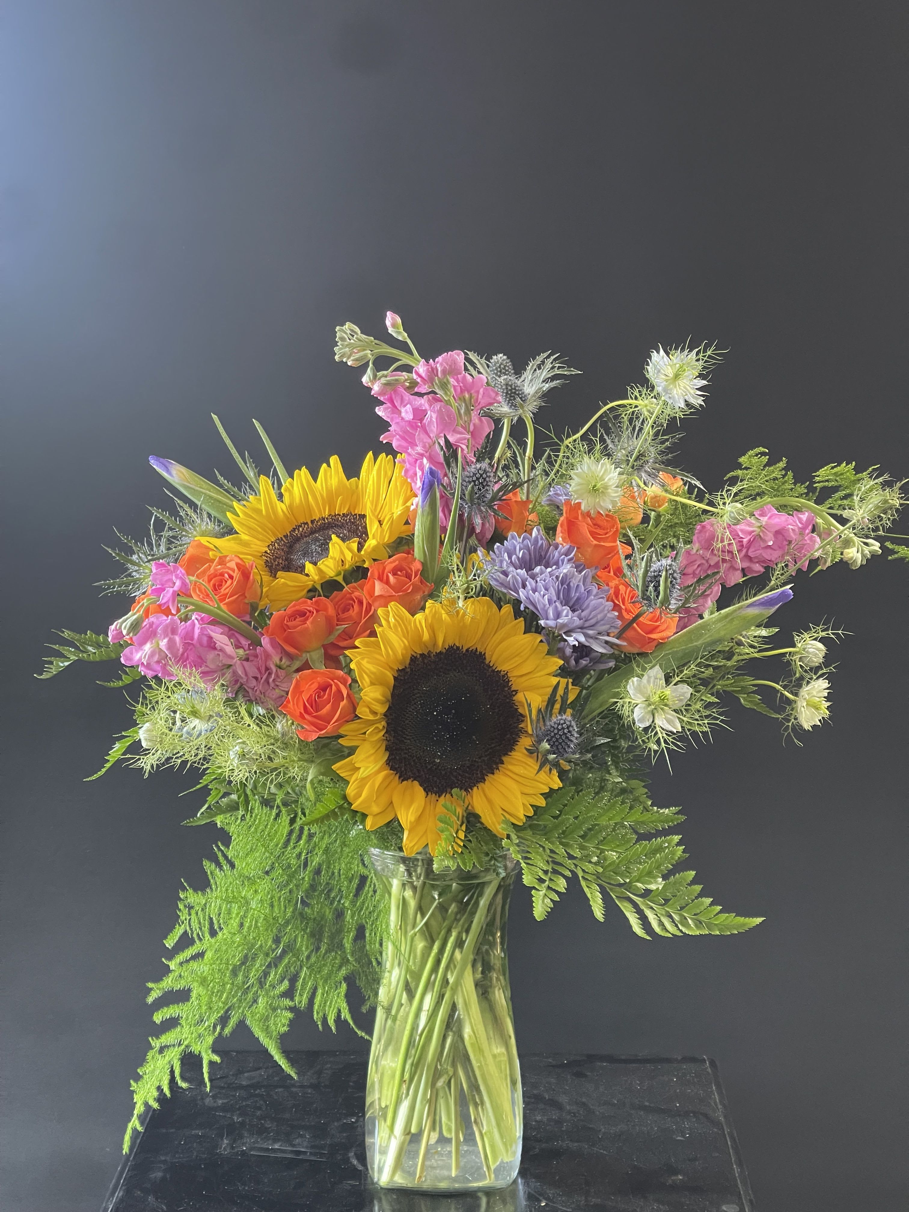 Sunflower and rose bouquet in a clear glass vase