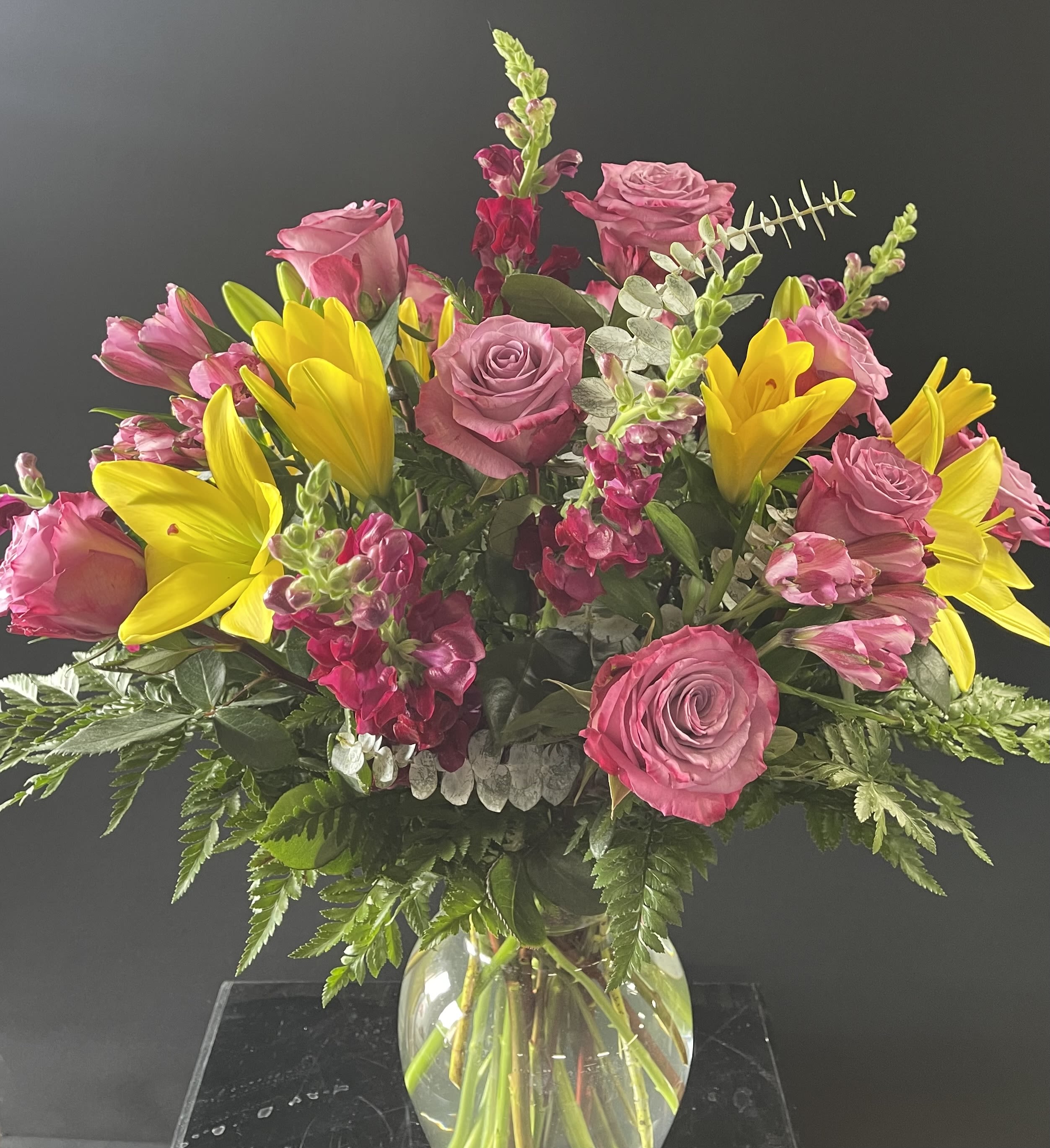 Pink roses and yellow lilies in a clear glass vase
