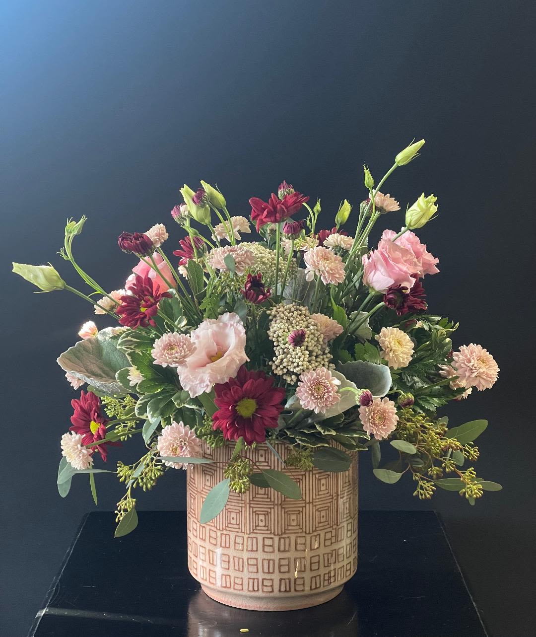 Mixed pink and burgundy flowers in a patterned ceramic vase