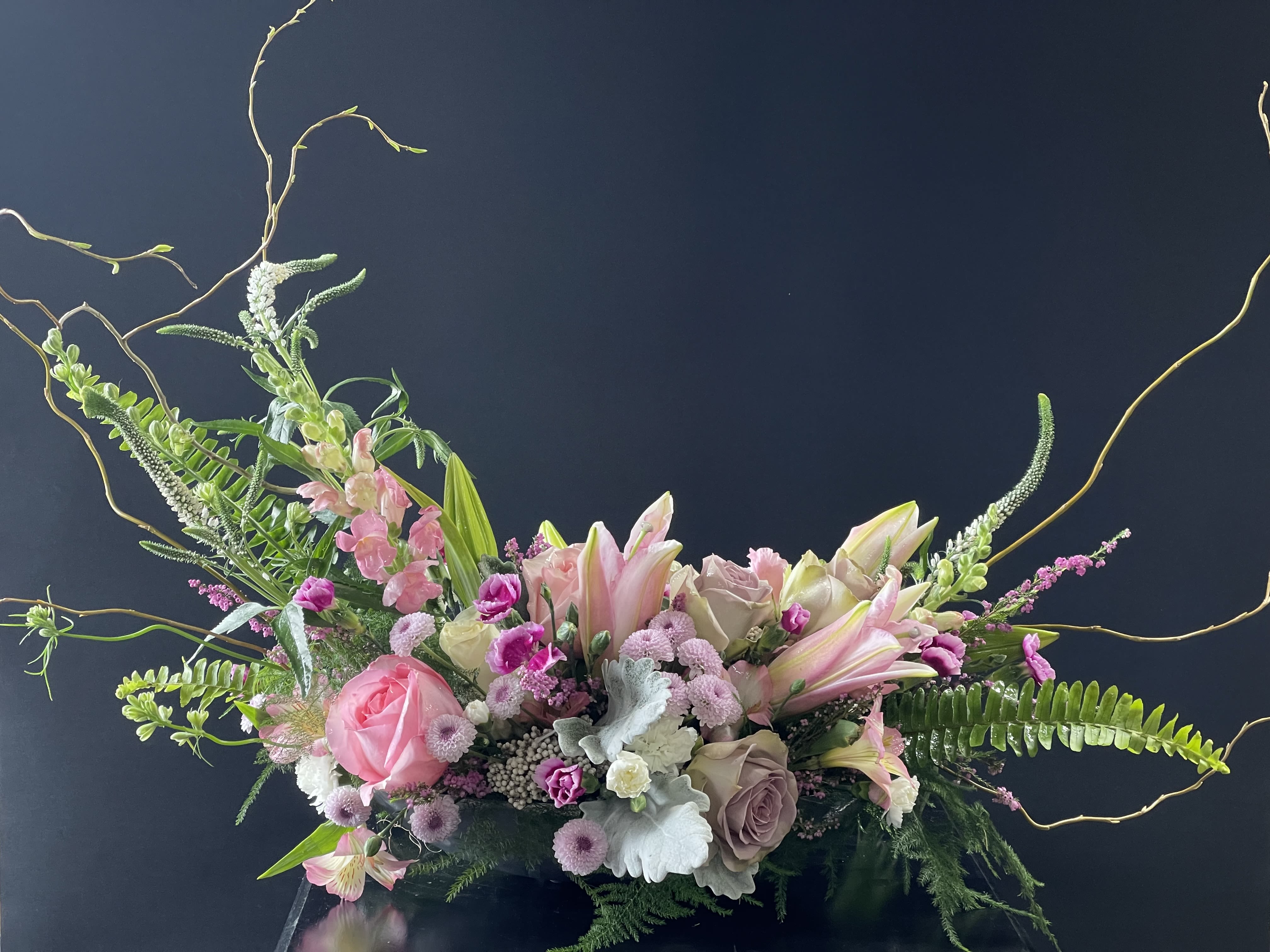Pink and white floral arrangement with lilies and roses in a low container