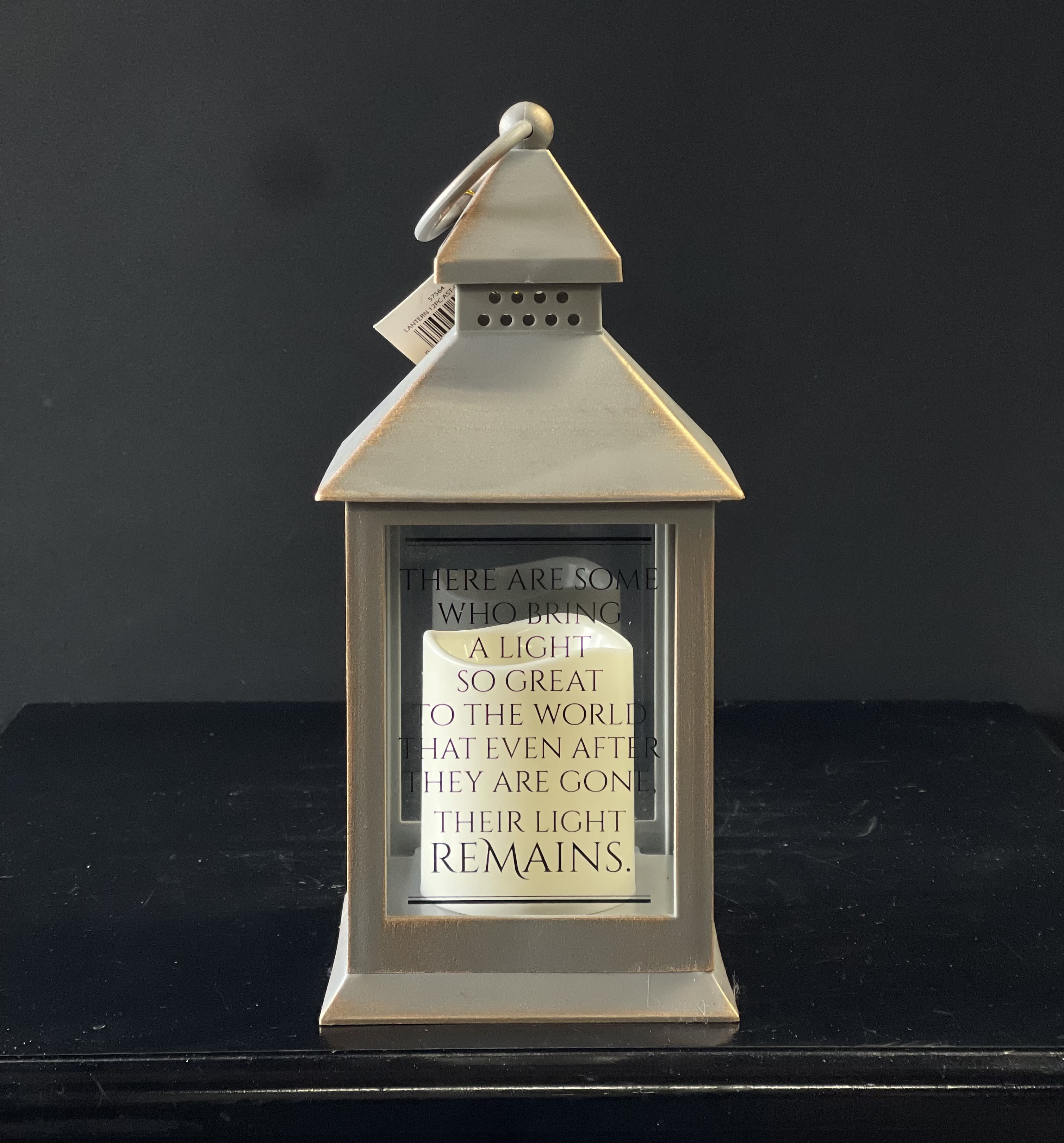 Beige metal lantern with glass sides, a memorial quote, and a white pillar candle inside.