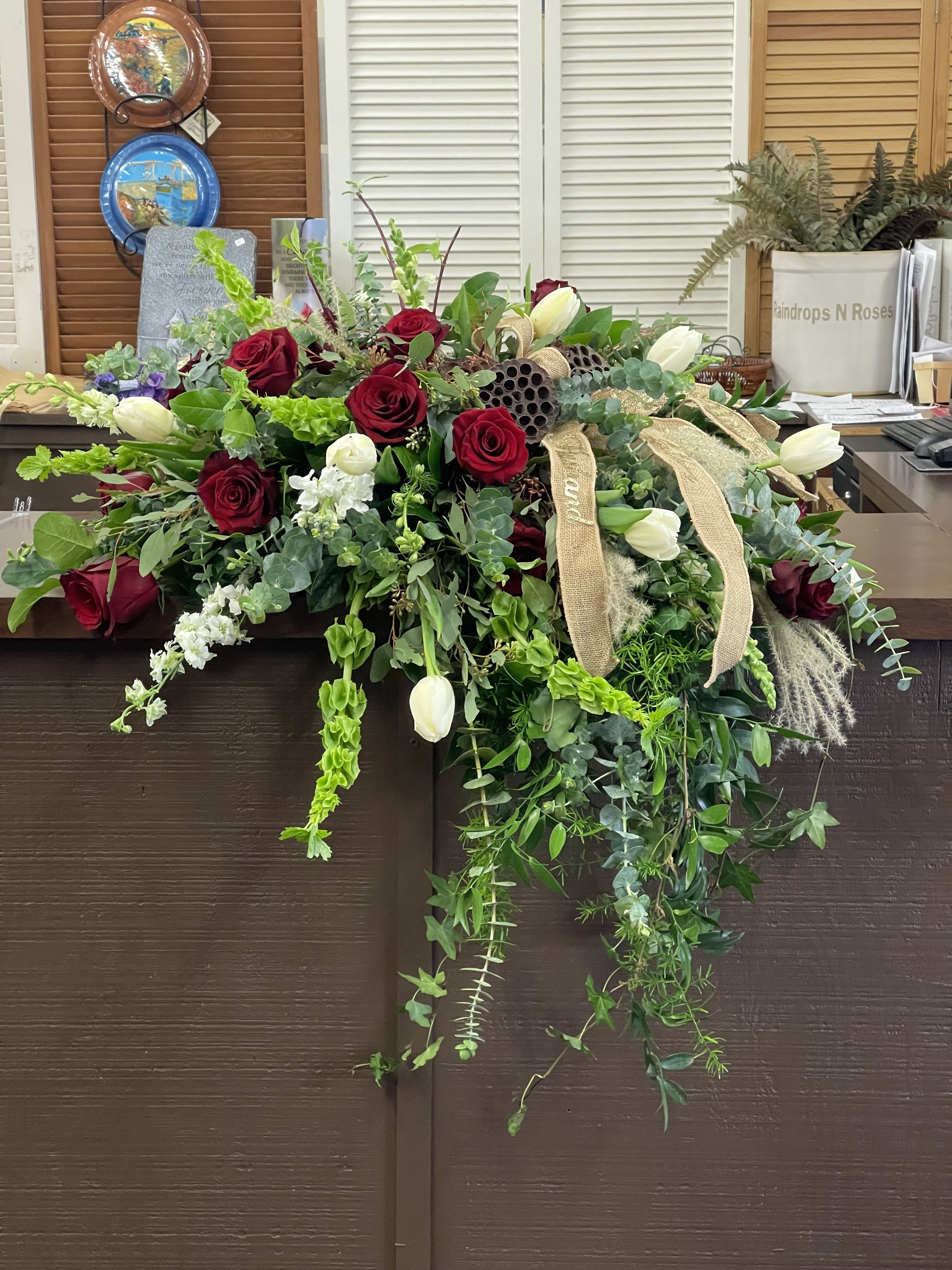 Large floral arrangement with red roses, white tulips, and trailing greenery