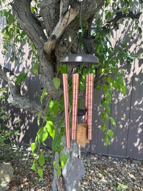 Copper wind chime hanging from a tree branch