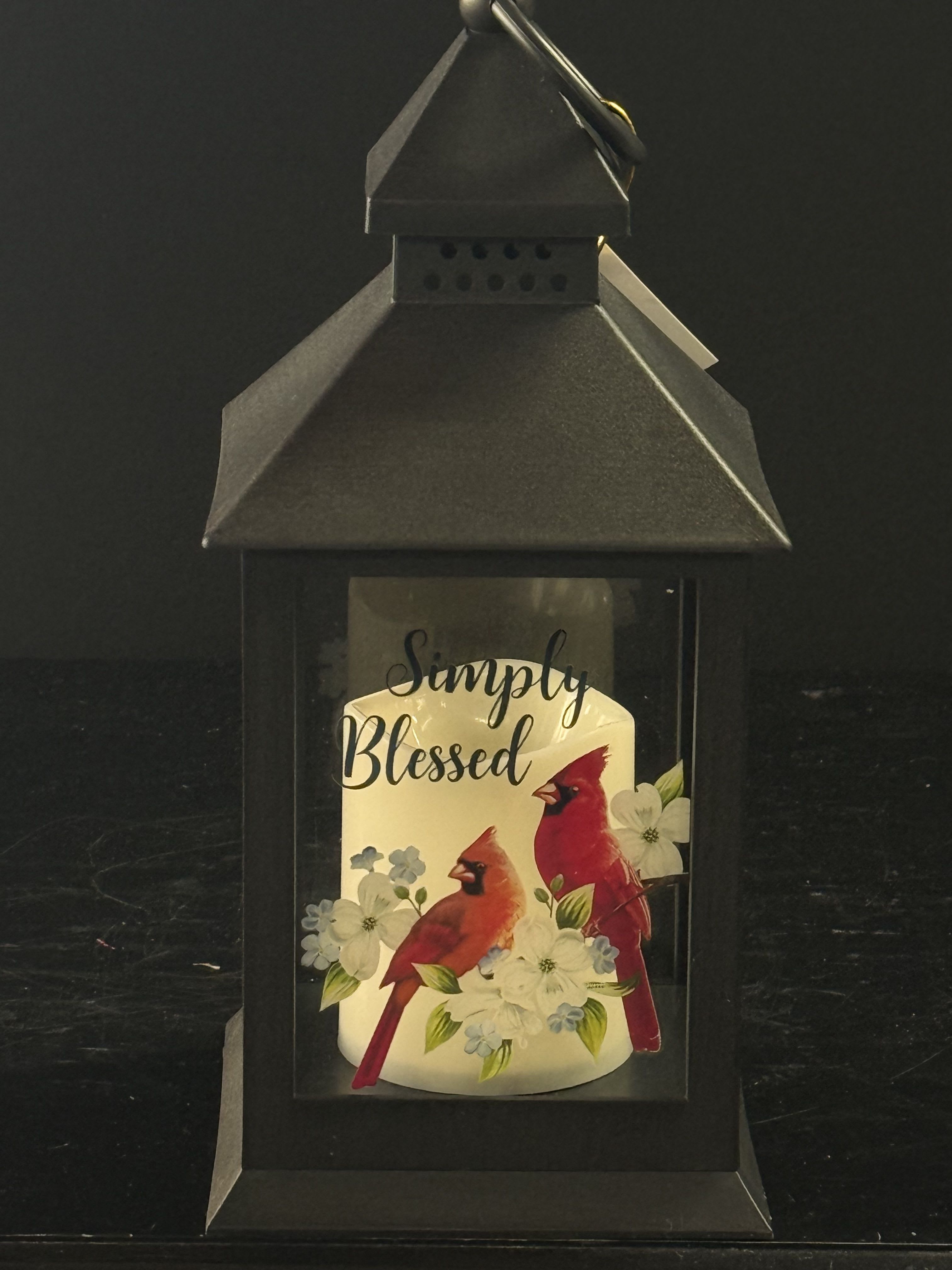 Black lantern with a candle labeled Simply Blessed and cardinals