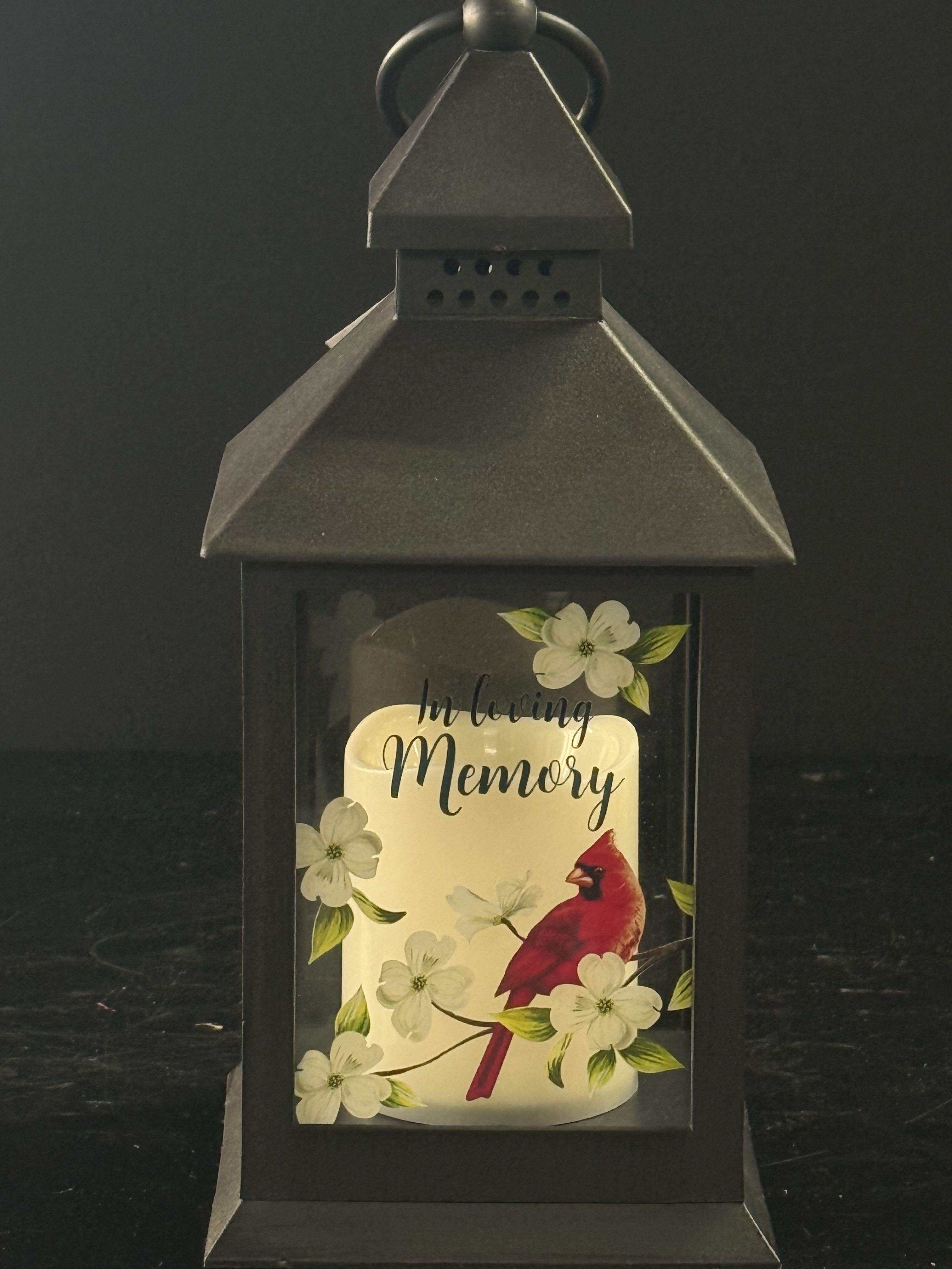 Black lantern with a candle and "In Loving Memory" card
