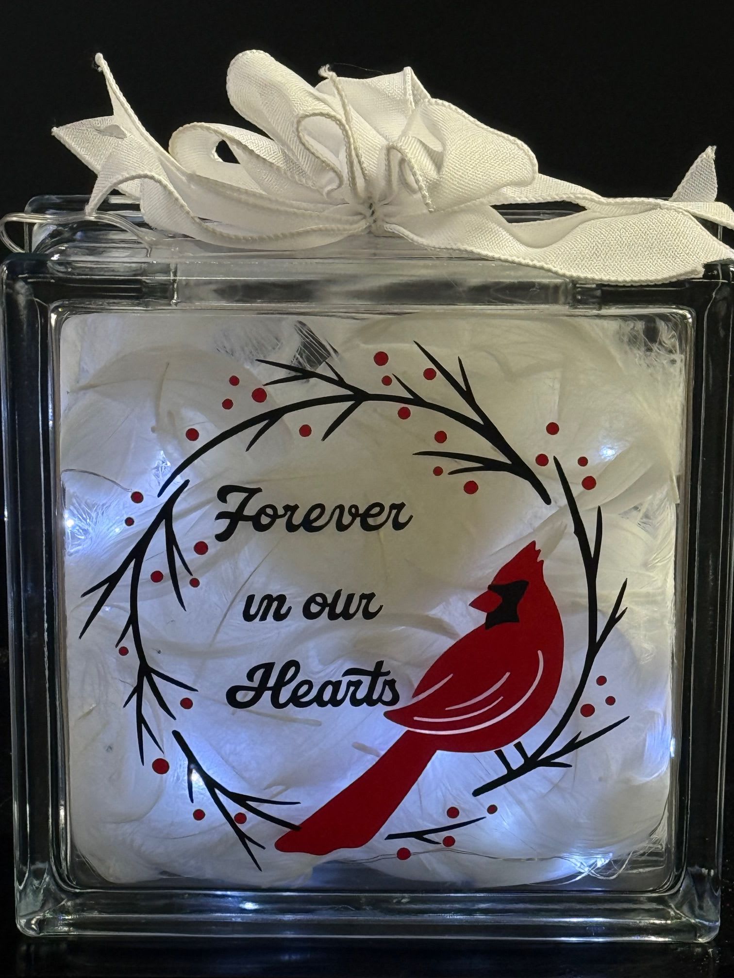 Illuminated glass block with red cardinal, memorial text, and white ribbon bow on top