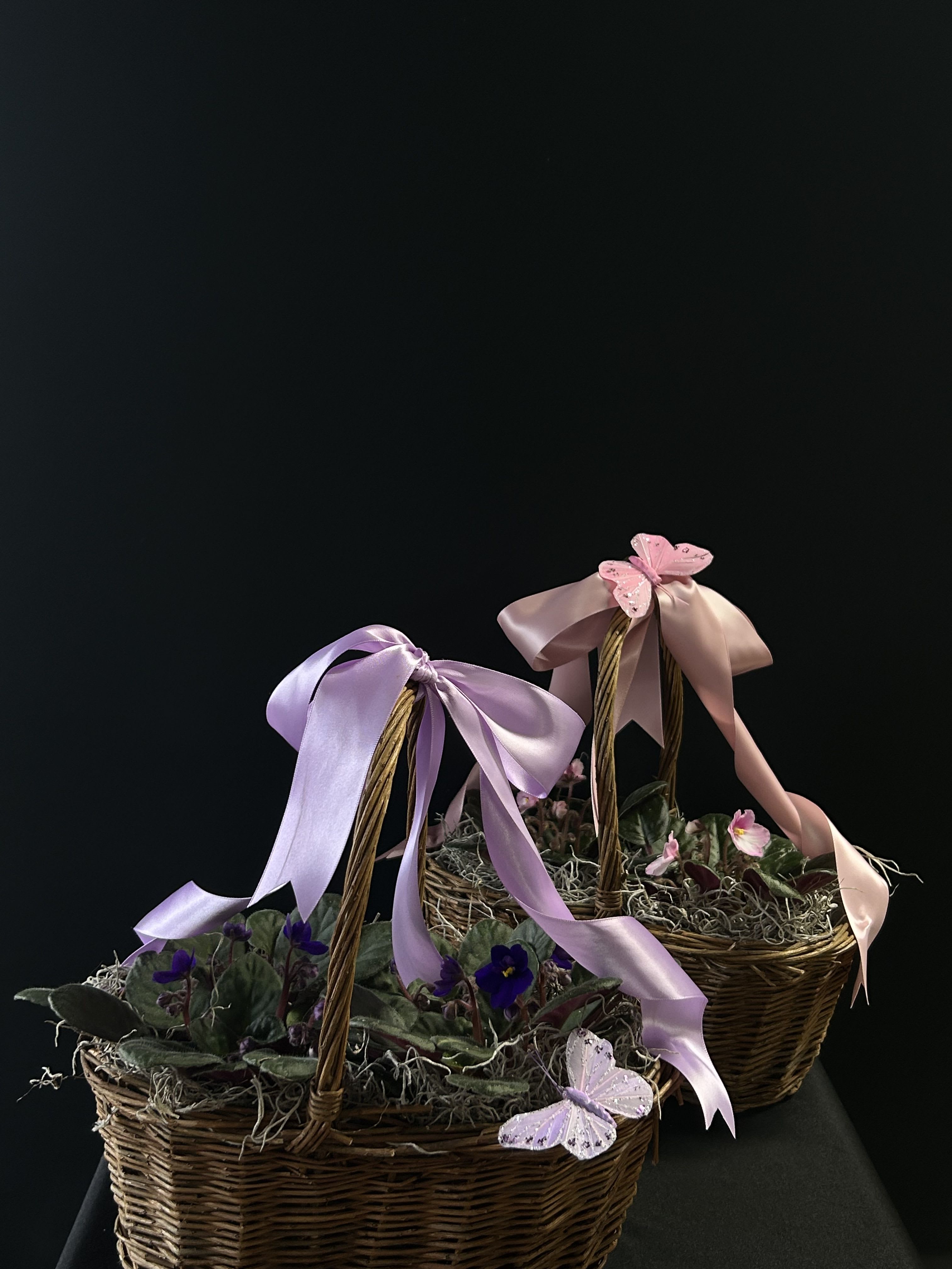 Two wicker baskets with small purple flowers and pastel ribbons