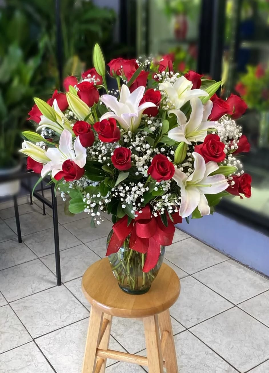 Red roses and white lilies in a glass vase with a red ribbon