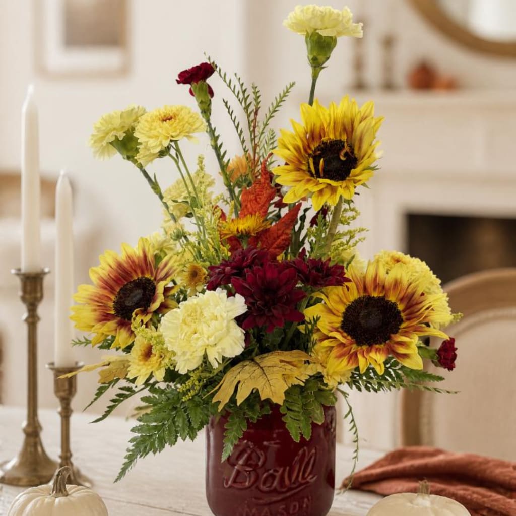 Sunflower and carnation arrangement in a red mason jar vase
