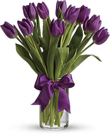 Purple tulips in a clear glass vase tied with a purple ribbon