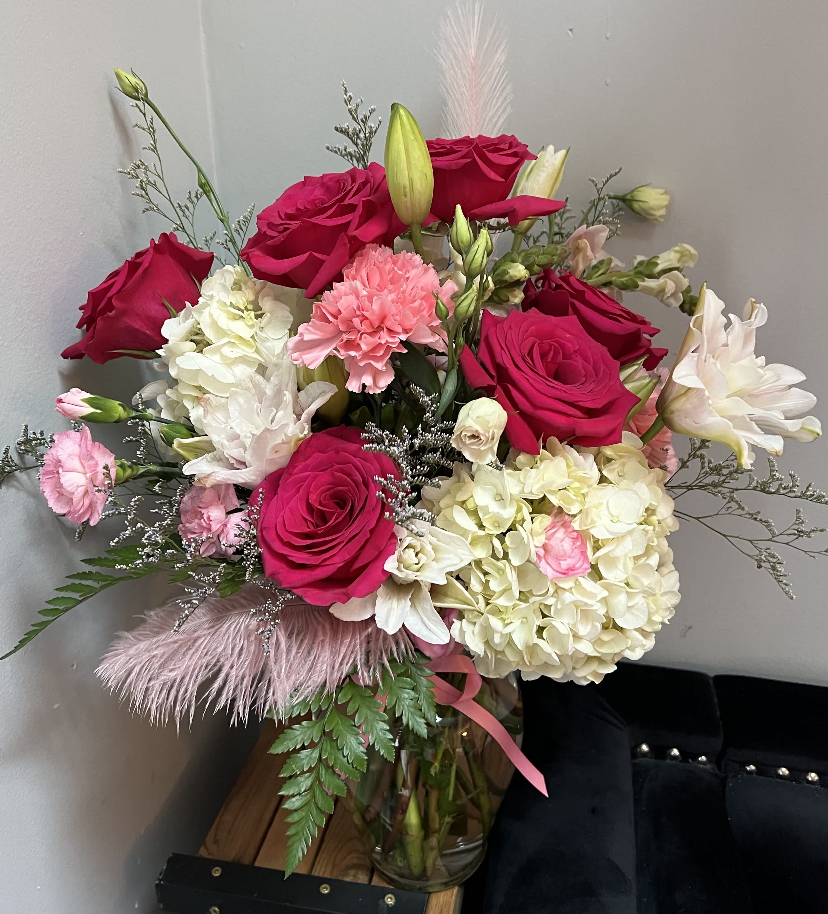 Bouquet of hot pink roses, white hydrangeas, and pink carnations in a glass vase