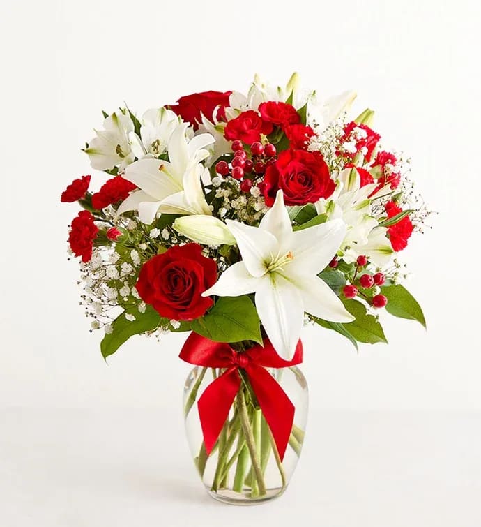 Red roses and white lilies in a glass vase with a red ribbon